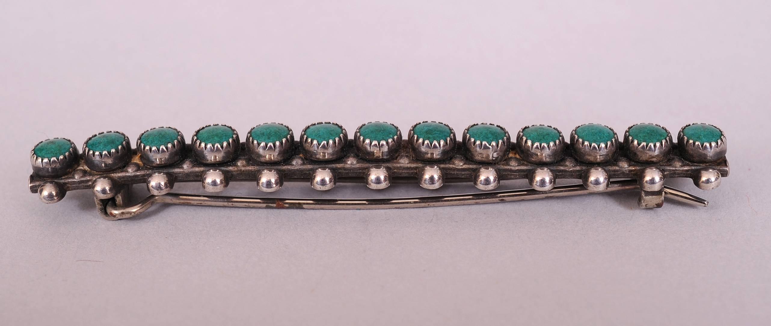 This Native American made hair barrette, a rare form, is made from silver and turquoise with a row of silver balls on either side of a row of matching turquoise stones. It is marked sterling on the back and it is in excellent