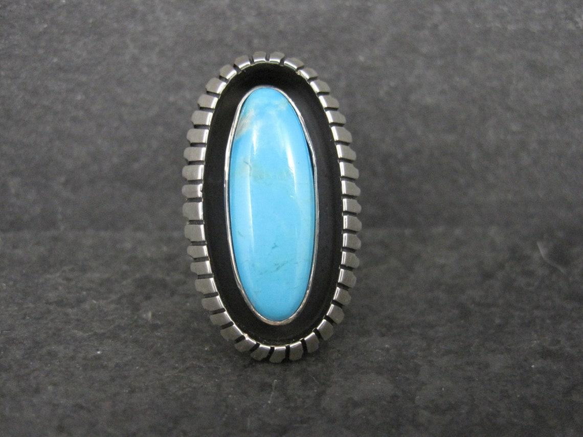 This gorgeous estate shadowbox ring is sterling silver with a kingman turquoise.
It is a creation of Running Bear shop.

The face of this ring measures 1 3/16 inches north to south.
Size: 8

Marks: RB, Sterling

Condition: Excellent
