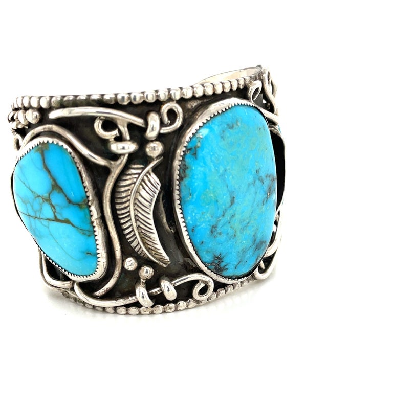 Three polished natural blue turquoise stones bezel set in hand tooled sterling silver are featured on this Navajo blackened sterling silver cuff.  Artful silver wire work whimsically decorates the cuff and a beaded edge detail finishes the piece.