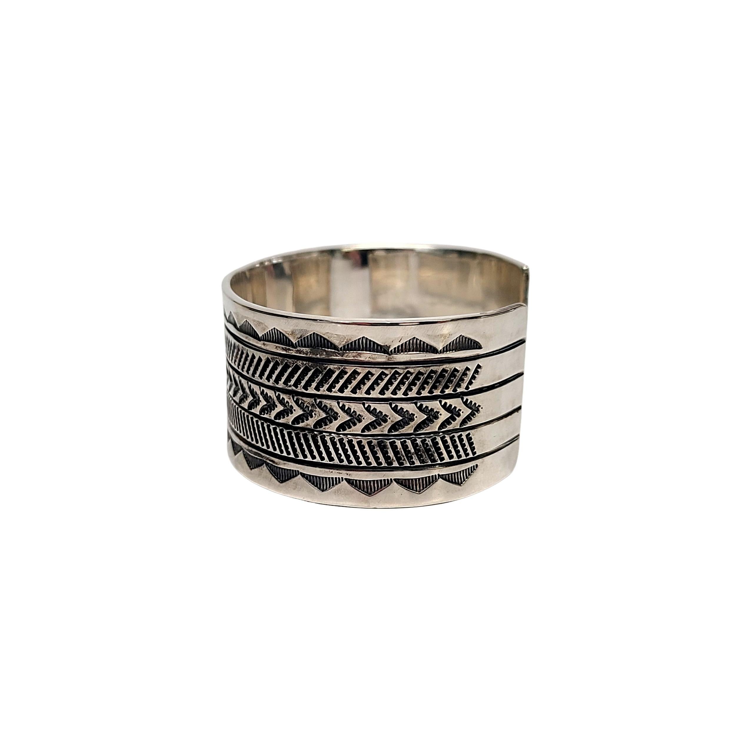 Manschettenarmband aus indianischem Sterlingsilber  von Zuni-Handwerker Myron Panteah.

Signiert mit Myron Panteahs Zeichen eines Bären, ist dieses Stück ein schönes Beispiel für seine traditionelle Stempelarbeit.

Maßnahmen ca. 5 3/4 