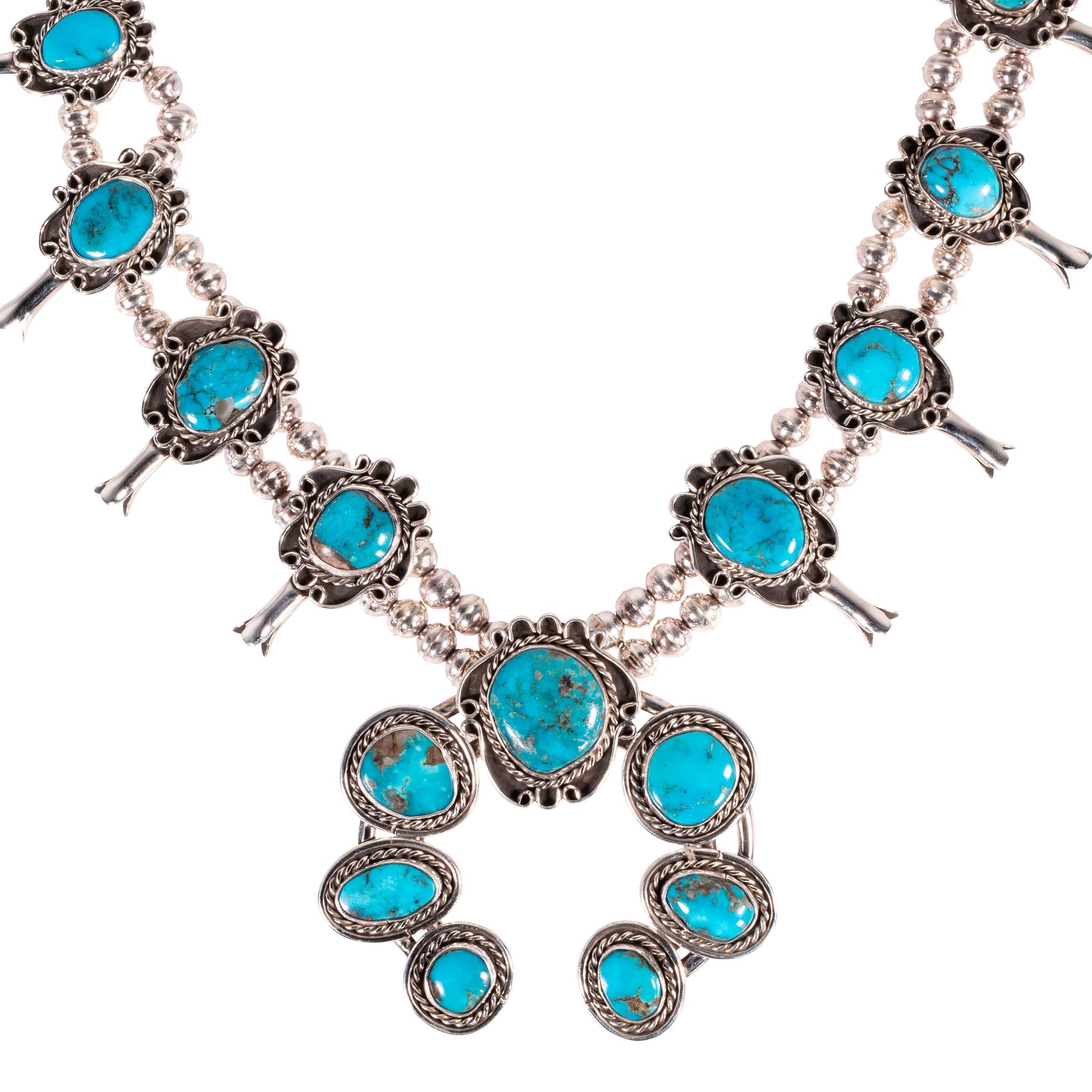 Bright sterling silver squash blossom with brilliant Bisbee turquoise stones. Each stone is set in scalloped shadowbox frame with twisted rope border. Stones feature beautiful brown and gold matrix- 17 stones total. Great for formal Southwestern