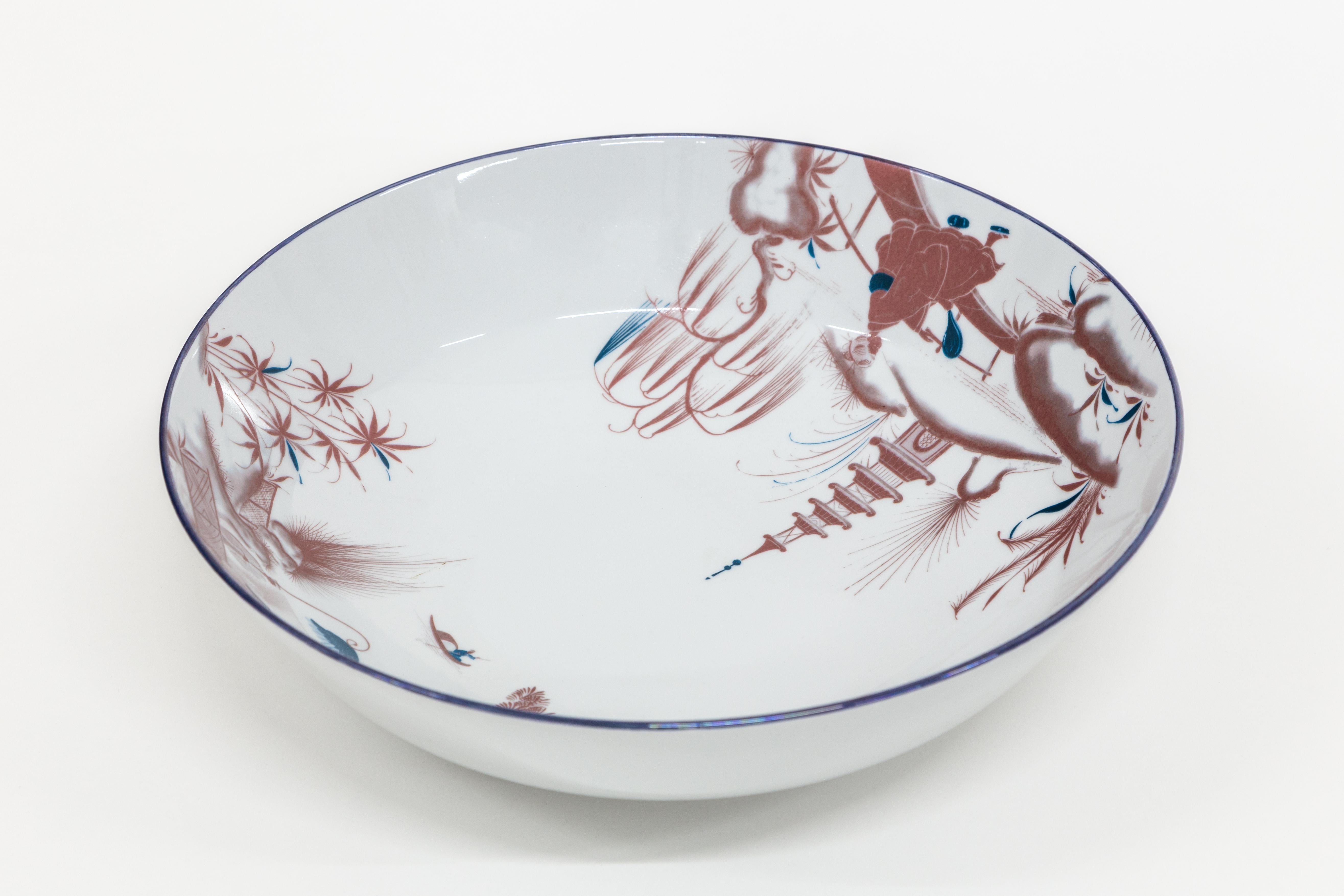 This 34cm diameter bowl is part of the Natsumi collection by Grand Tour By Vito Nesta. The very versatile shape is suitable as a fruit stand, table centerpiece or ornamental bowl on any shelf. In the inner rim of the bowl take place two scenes of