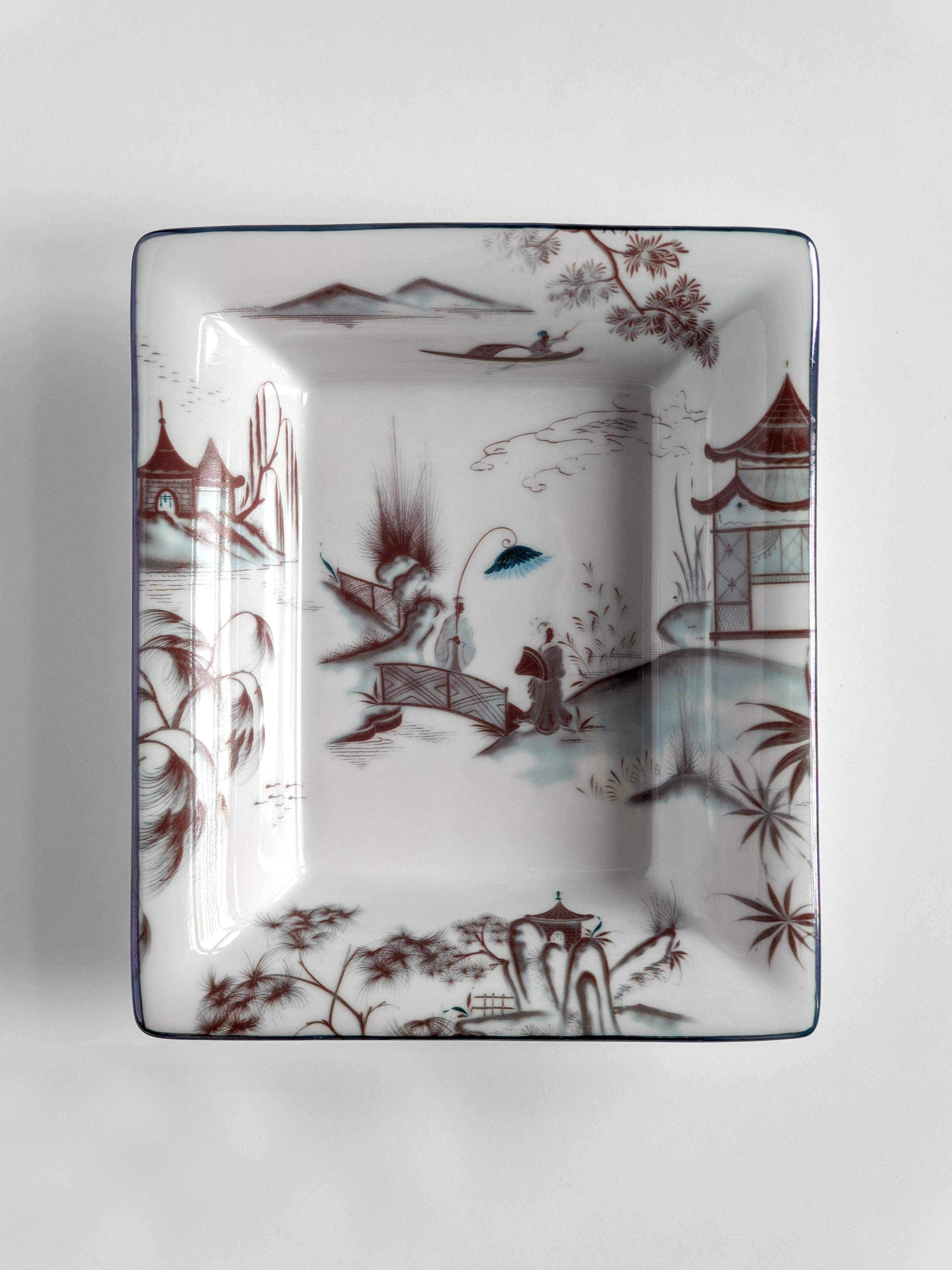 A set of two porcelain pocket emptiers/ashtray with a classic shape and unique printed design. Natsumi vase evoke dream-like images of Japanese landscapes. Rendered in the Imari tradition, the dominant color is reddish-orange, while a striking touch