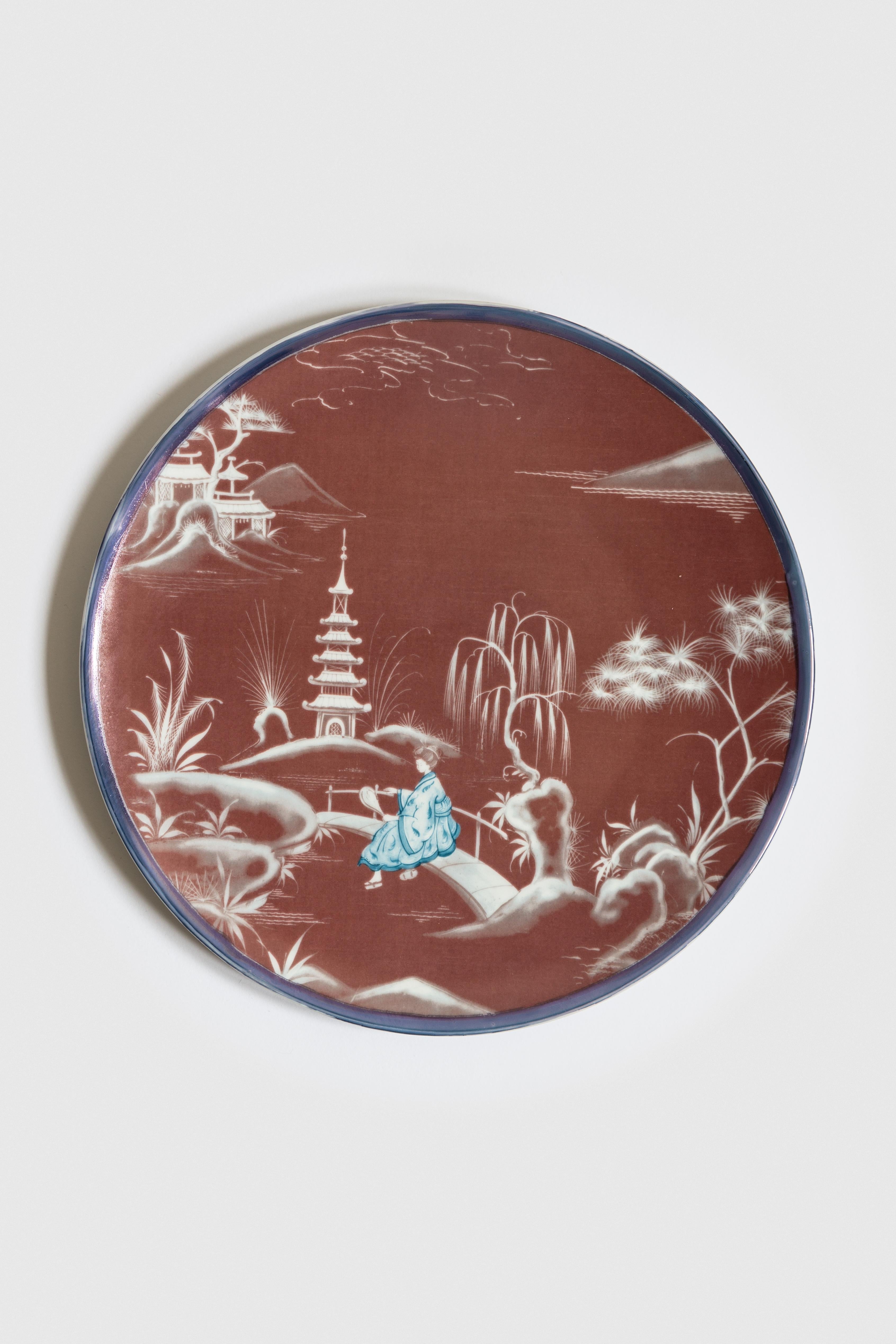 Bordeaux and blue are the primary colors of this Japan inspired collection of plates, where ancient Japanese scenes take place on the rivers of a fairy lake.