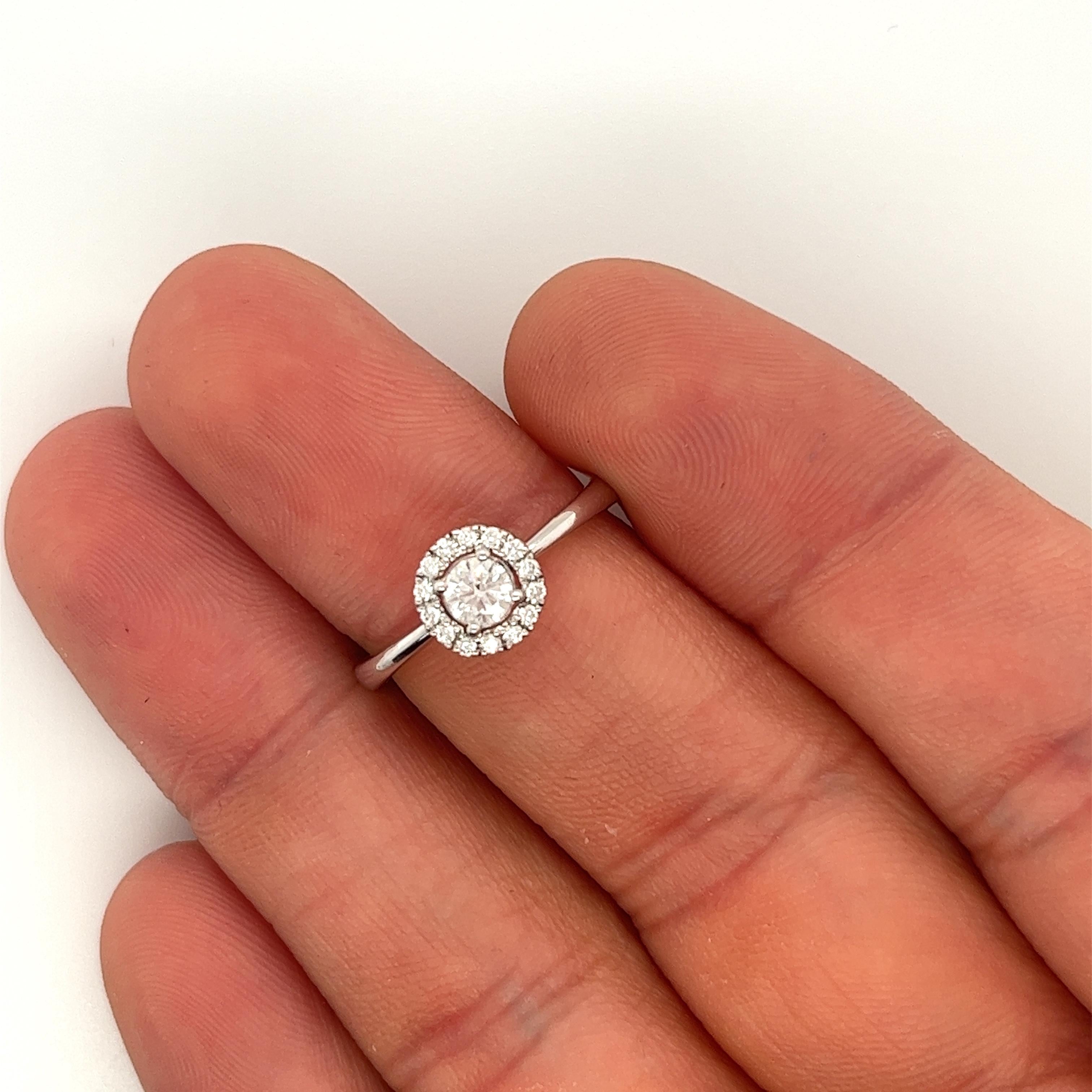 Natural 0.22 Carat Round Cut Diamond Ring in 14K White Gold. Featuring a dazzling 0.22 carat Round Cut Diamond as its centerpiece, color F-G and SI1-SI2 grade clarity. Sized at 6.5, this ring boasts a classic 2MM band, 7.5MM halo, and a pinches ring
