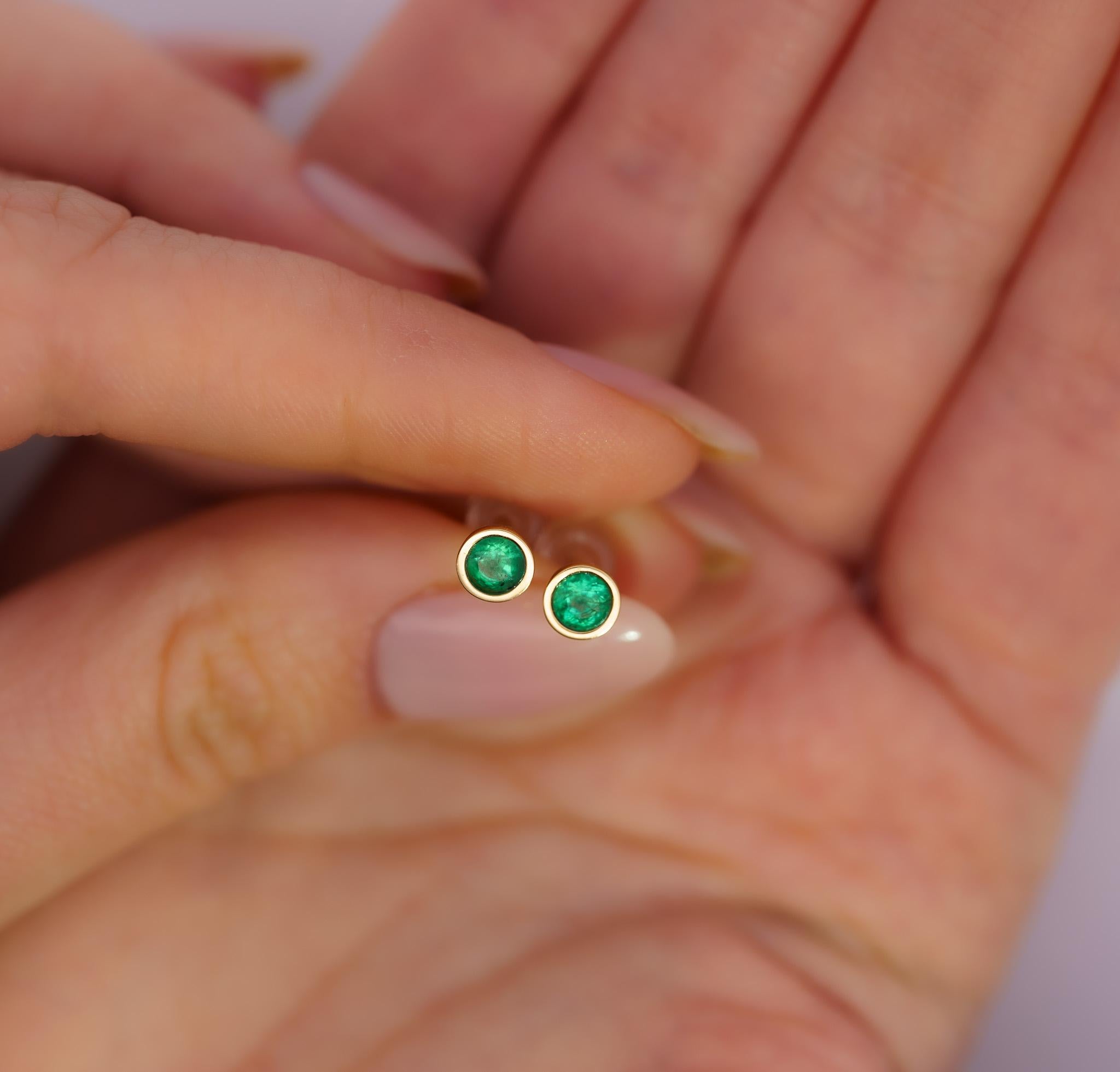 Natural 1/2 Carat Emerald Stud Earrings in 14K Yellow Gold. 

These modest emerald earrings boast two round-cut emeralds with a total carat weight of 0.50; the emeralds are safely secured with a bezel setting. The 5 MM (each) studs are crafted from