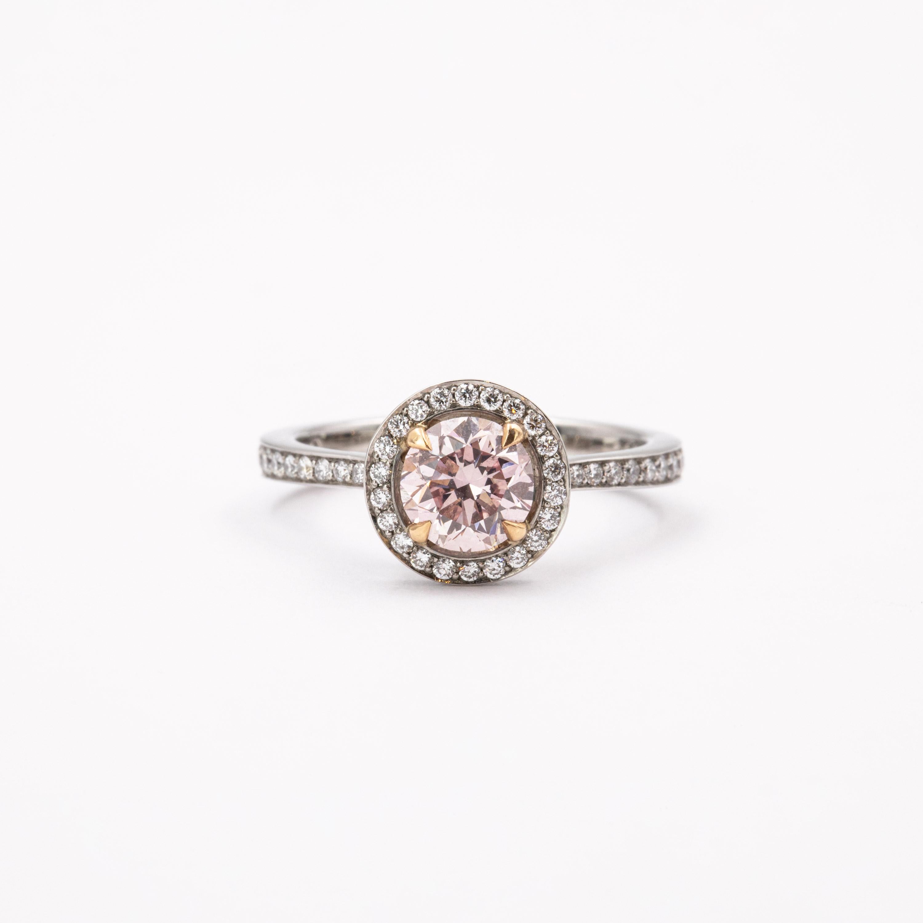 A natural fancy intense pink diamond (HRD certified), weighing 1.01 carats, is the heart of this enchanting piece. A delicate circle of white diamonds surrounds the centerstone, floating above a hidden halo which unites the pavé-set shank’s ends.
