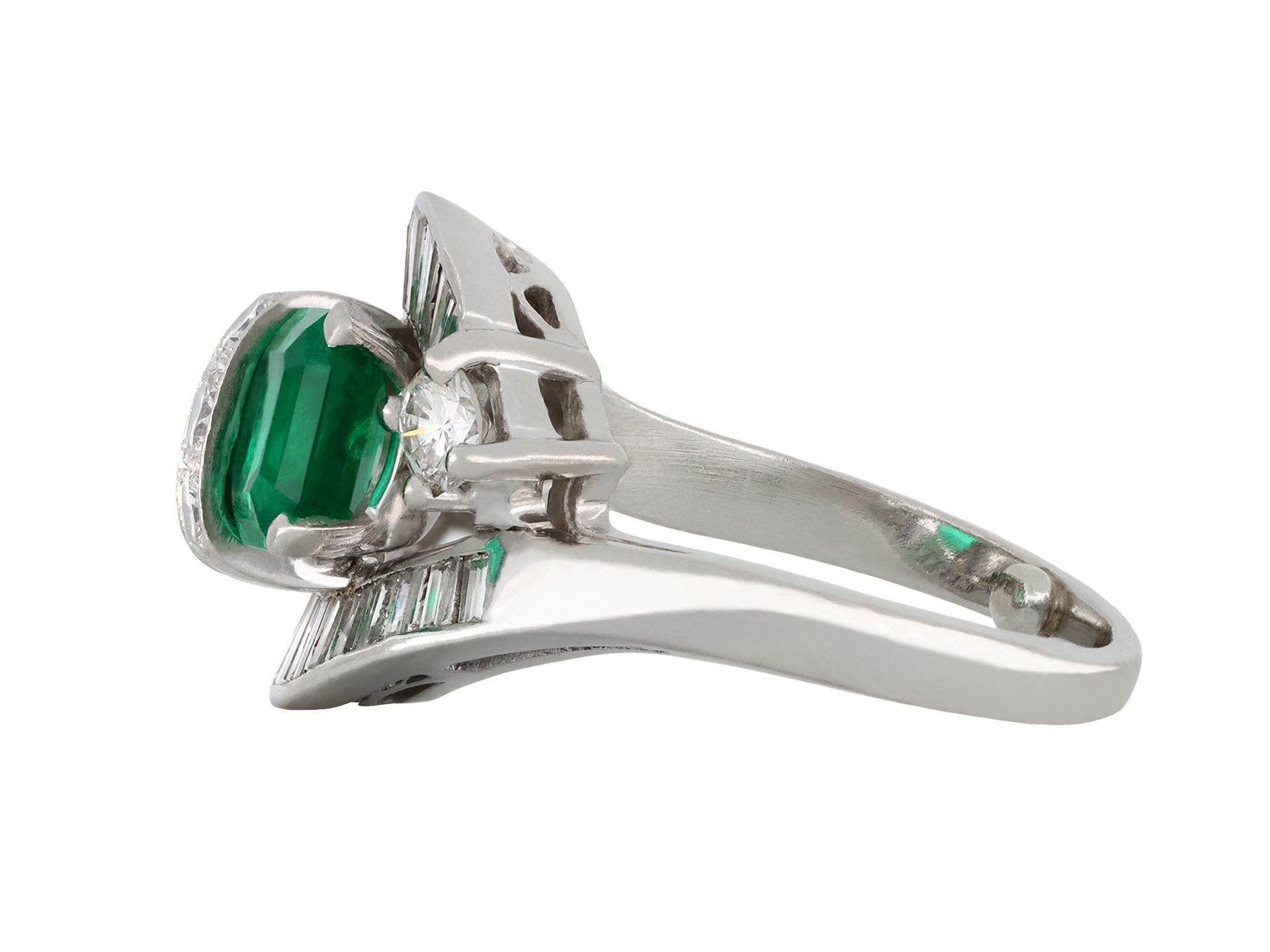 Emerald and diamond crossover ballerina ring, circa 1950. A platinum and iridium ring diagonally set with one rectangular emerald-cut Colombian emerald in a claw setting with an approximate weight of 1.10 carats, and one rectangular emerald-cut