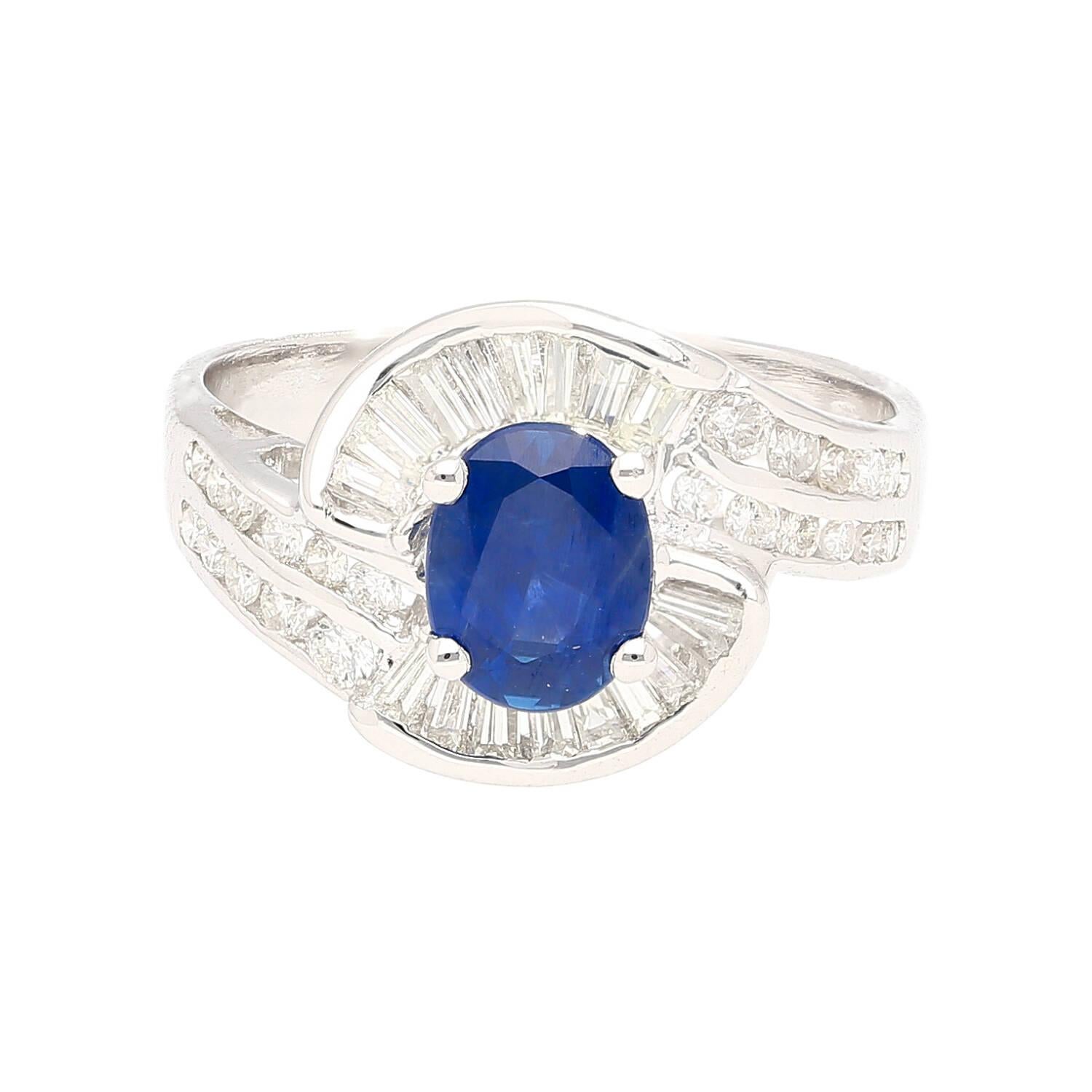 A natural 1.14-carat oval-cut blue sapphire takes center stage in this exquisite 18K white gold ring. The mesmerizing blue hue of the sapphire is complemented by a cluster of round and baguette-cut diamonds, adding brilliance to the swirling