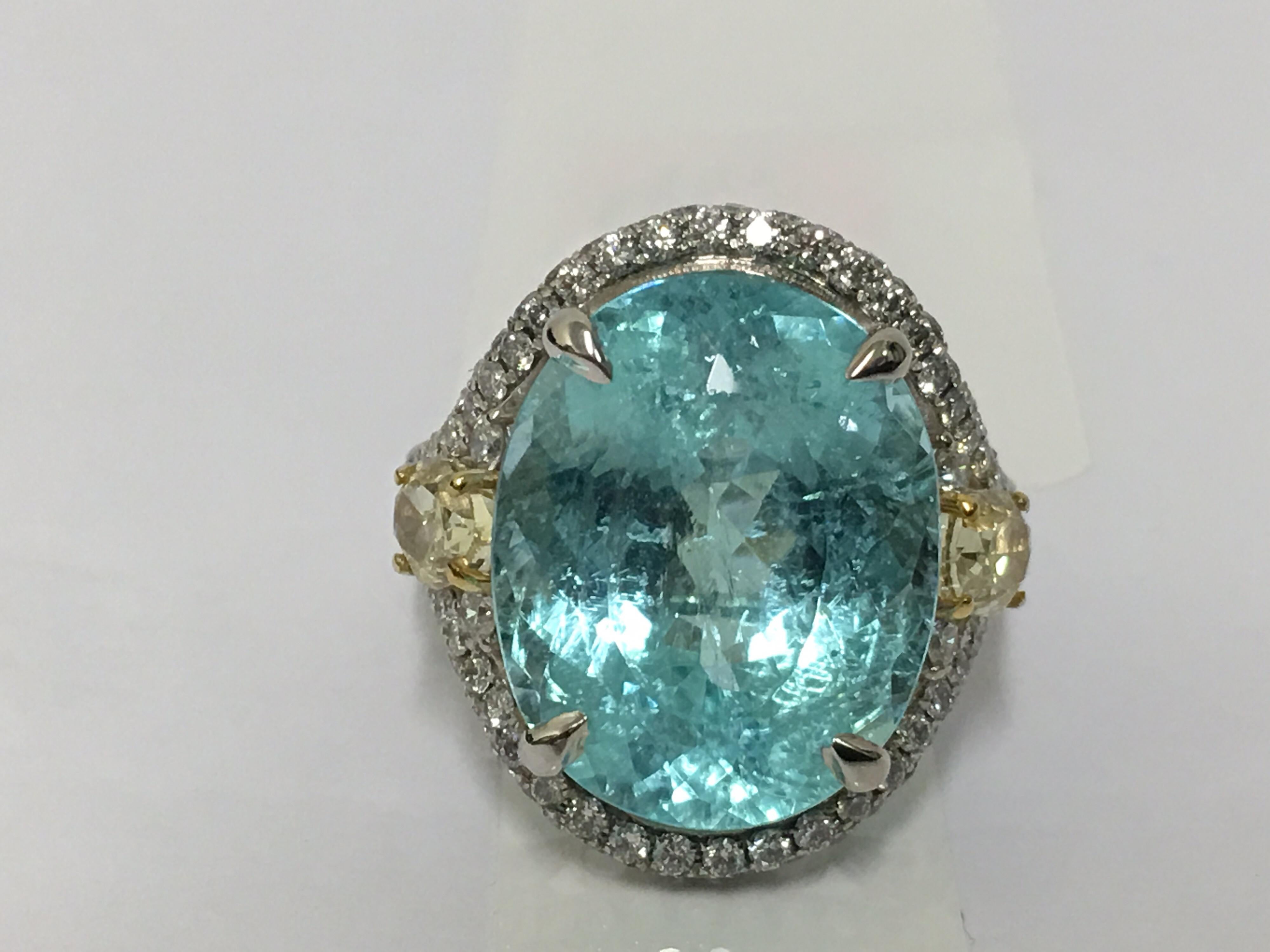 Natural 13.01 Carat Copper Bearing Paraiba Tourmaline is oval shape Stone Set in 18 Karat two tone gold .
Yellow diamonds is 1.05 Carat and other halo white round diamond is 1.03 Carat total. Size of the Ring is size 7 and if needed can be resized.