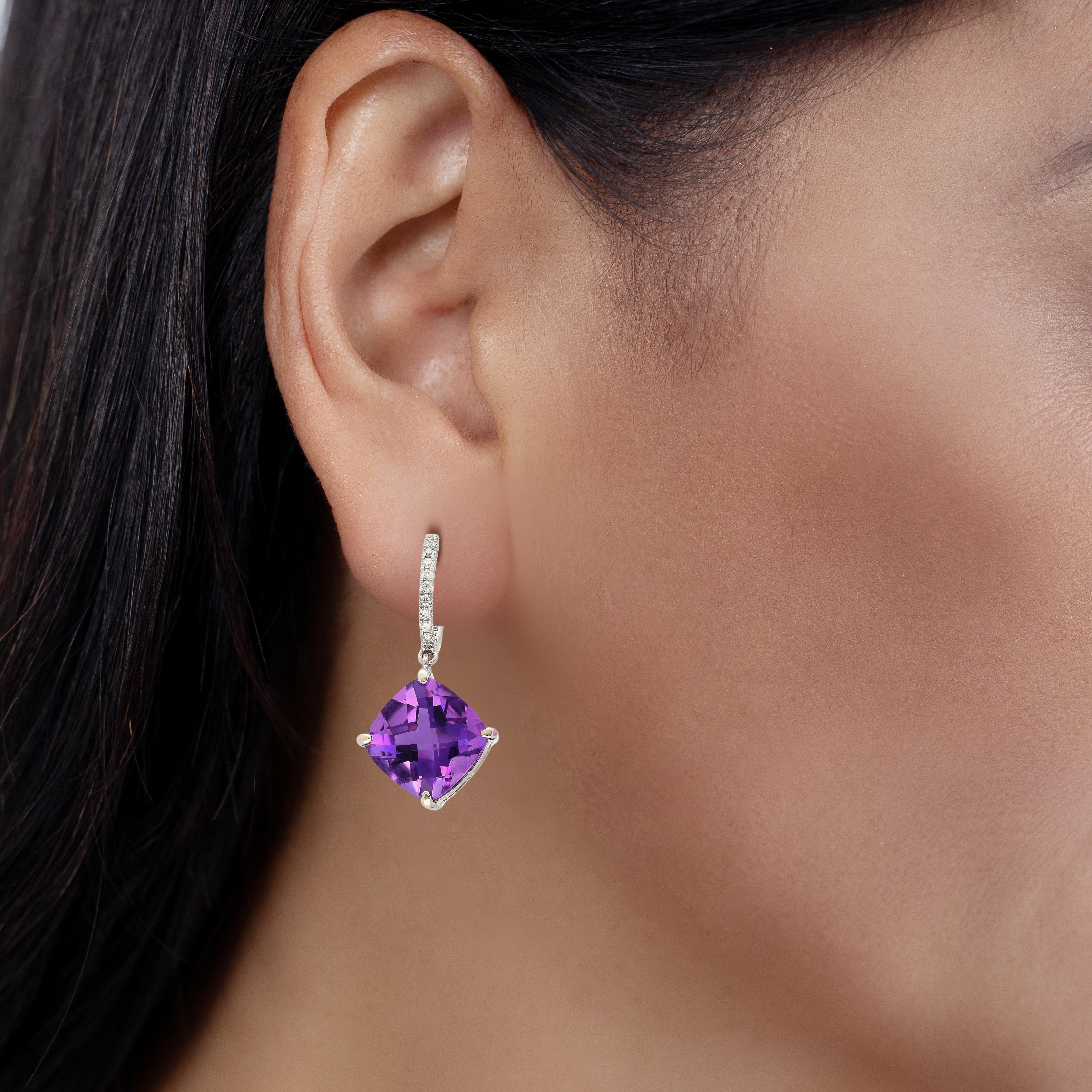 These mesmerizing earrings feature a captivating duet of cushion-cut amethysts, totaling 13.12ct together, their rich purple hues shimmering with elegance. Secured in delicate prong settings, the amethysts gracefully dangle from lustrous 18k white