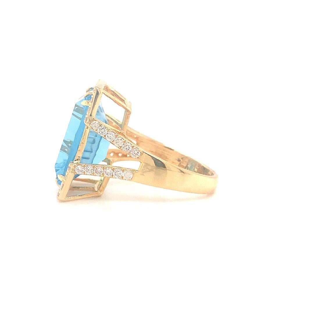 An beautiful ring of 13.20 carat natural emerald cut blue topaz surrounded by 0.91 carat diamonds set in 18 karat yellow gold.  