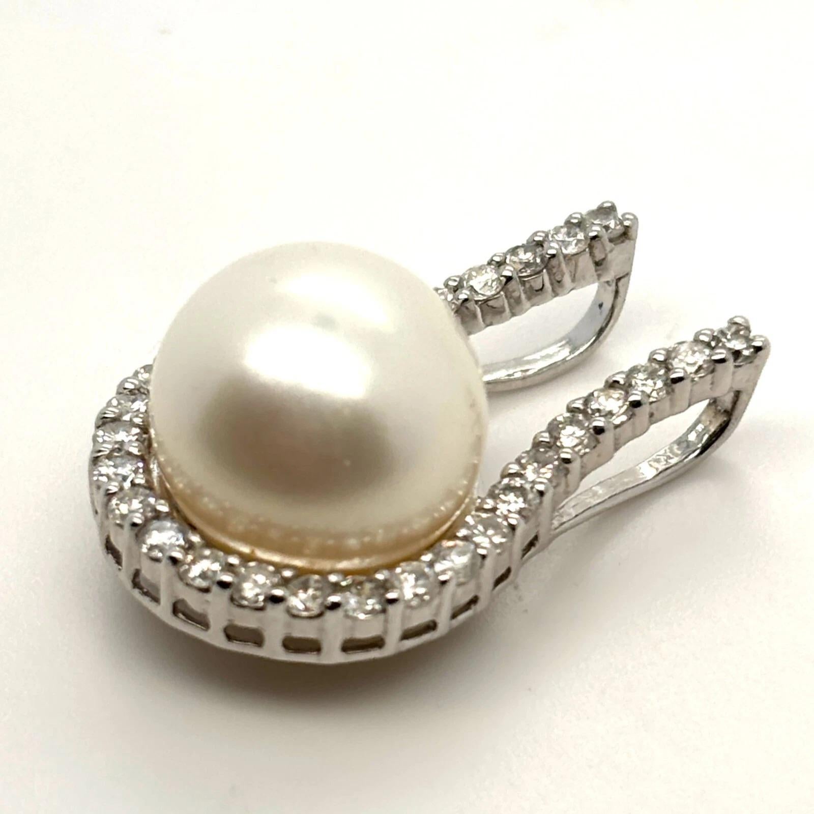 Offered is an elegant white pearl and diamond slide pendant, crafted in solid 14K white gold. The pendant showcases one luminous round cultured white pearl measuring approximately 11mm in diameter, set at the center of a gracefully arched design.