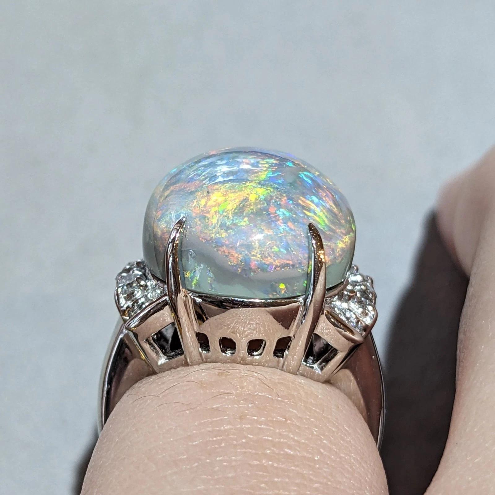 Natural 18.70 carats Black Opal and Diamond Ring in Platinum 

Large Opal and Diamond Ring features one Oval High Dome Cabochon Black Opal with Green, Orange, Yellow, and Blue Play-of-Color on adGrey Background accented by Natural Round Brilliant