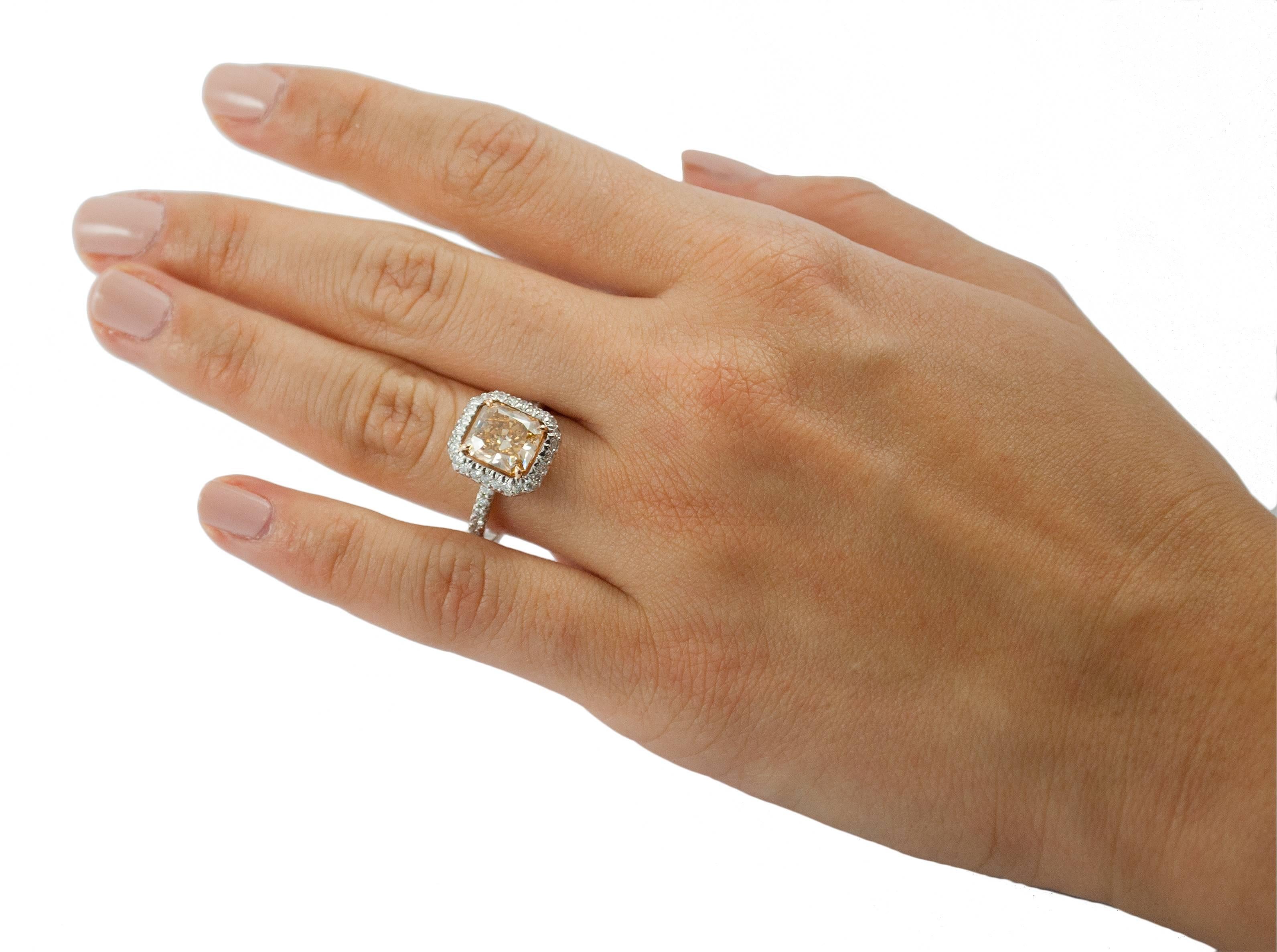 This ring features a 2.01 carat cut-cornered rectangular modified brilliant diamond, of VS2 clarity, which has received a color grade of fancy brownish orangey yellow. It is set on a platinum band with 18kt rose gold prongs. White diamonds are set