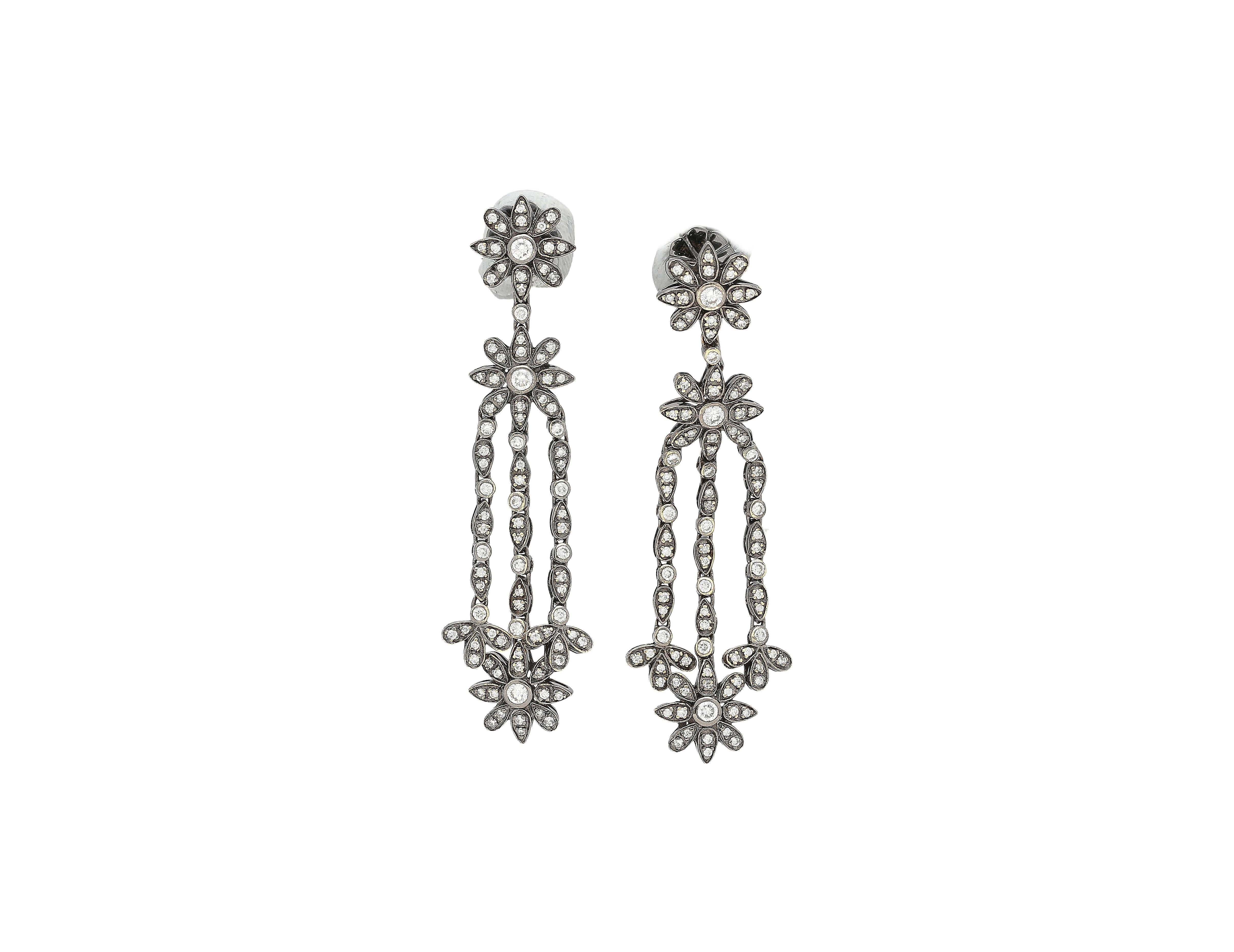 Natural Diamond Dangle Drop Earrings in 18K White & Black Gold.

These earrings feature a floral design made from round-cut diamonds as well as an additional diamond side stone, with a total weight of 5 carats. Each diamond detail is secured using a