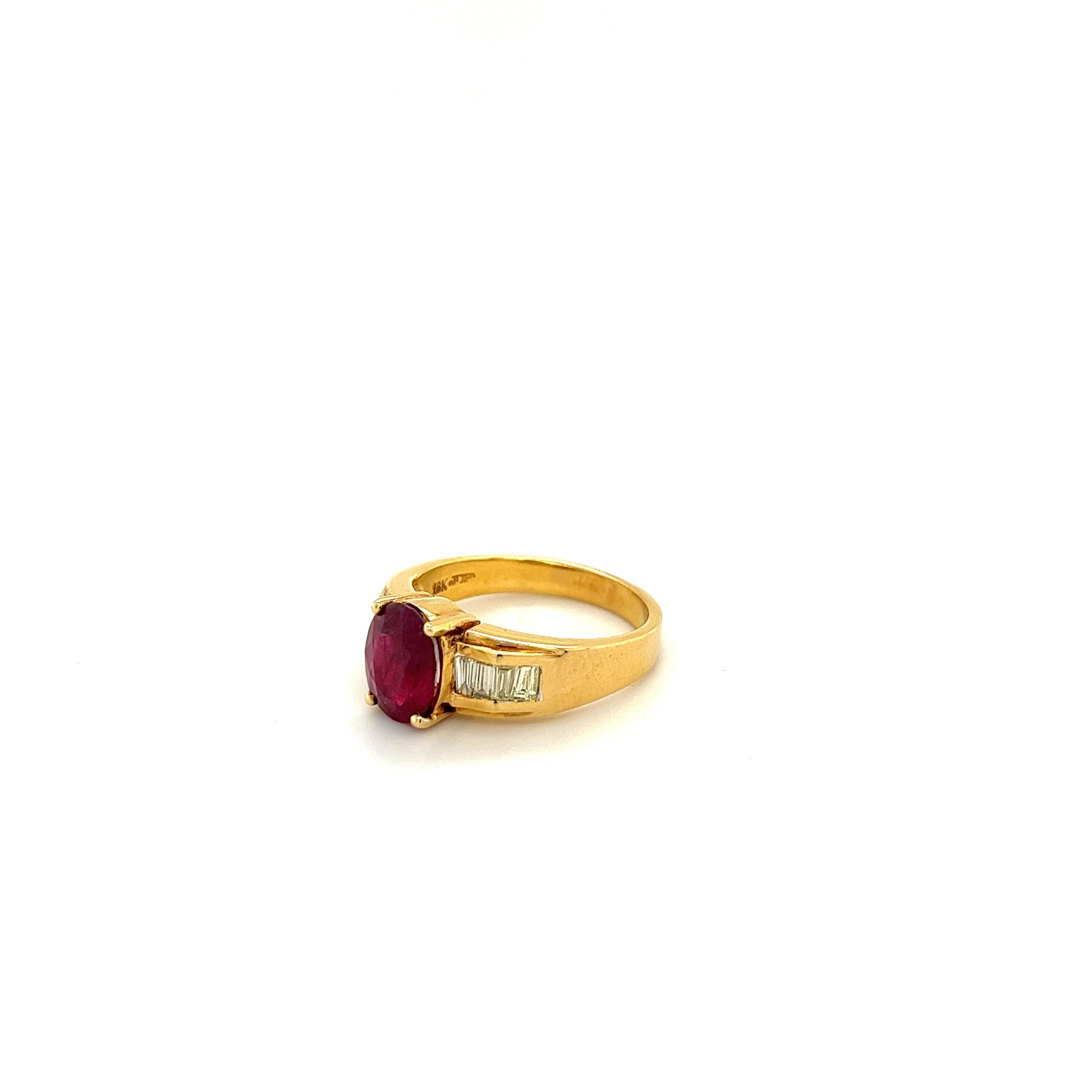 Oval-cut natural Ruby adorned with natural Baguette-cut diamond side-stones. Gemstones are mounted in a straight shank 18k gold classic setting. The center stone Ruby has flawless clarity and refracts deep bright red color hues. Especially under