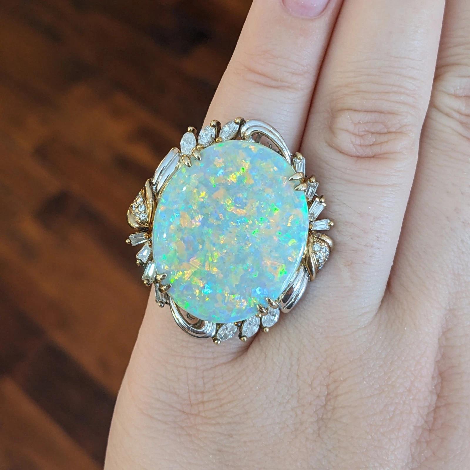 Bague en platine et or jaune 18k avec opale naturelle de 22,69 ct et diamant

La bague en opale et diamant présente une opale blanche naturelle de forme ovale pesant 22,69 carats avec des jeux de couleurs orange, rose, vert, jaune et bleu, accentués