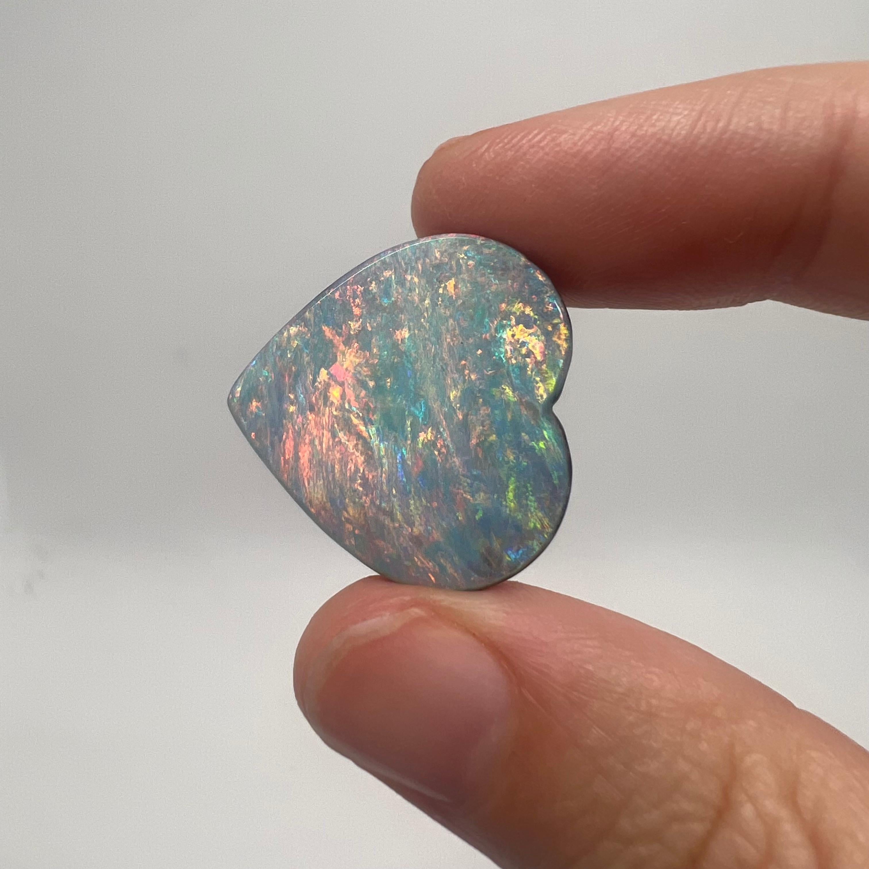 This large natural solid Australian boulder opal was mined in western Queensland, Australia by a female opal miner. It is of gem quality and its heart shape make it a very sought-after piece. Its colors are all bright and include pink, orange, aqua