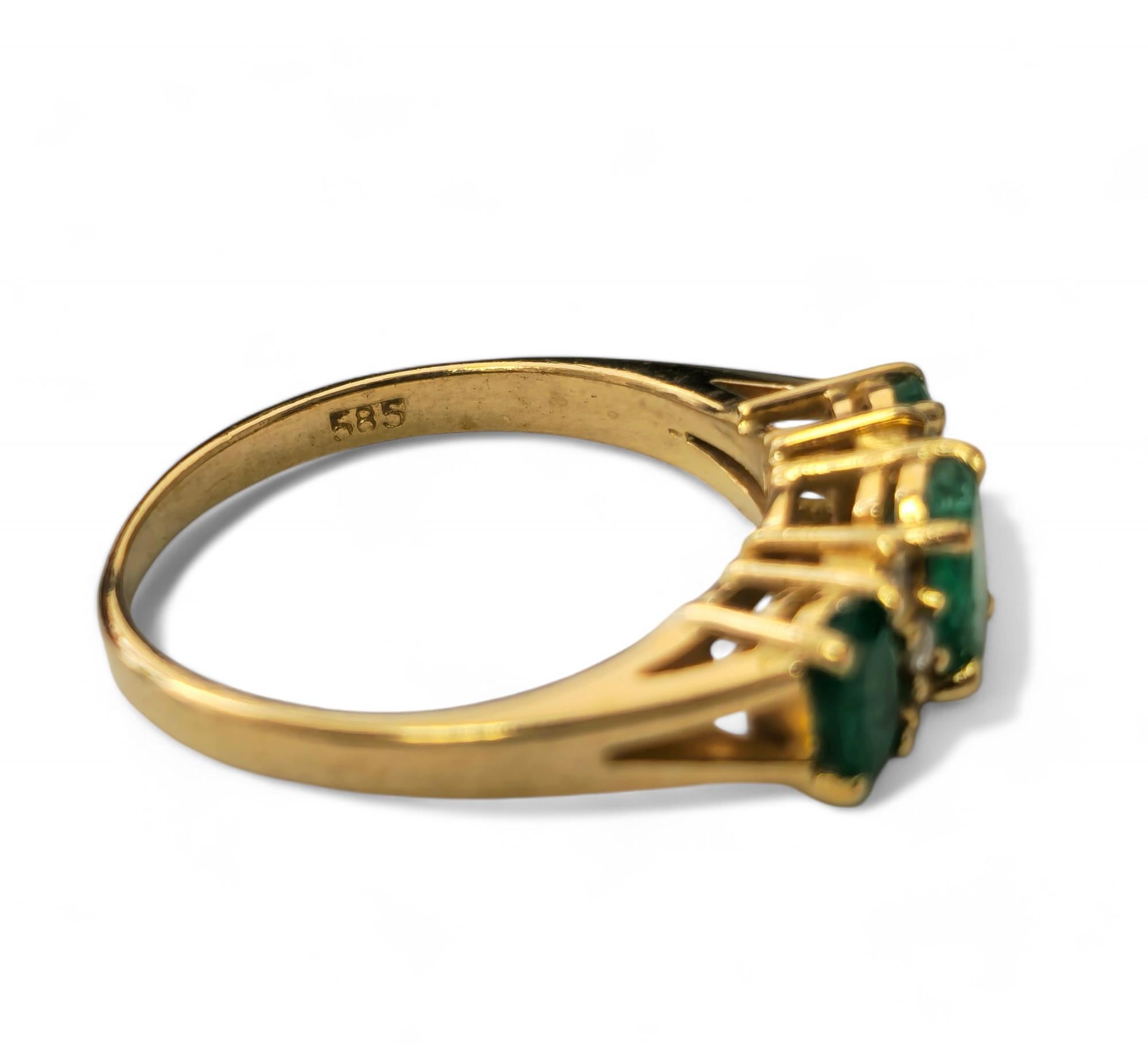 Dieser aus 14-karätigem Gelbgold gefertigte Vintage-Ring besticht durch einen 1-karätigen Smaragd im Ovalschliff, der von insgesamt 0,25 Karat natürlichen Diamanten aus Erdminen mit den Reinheitsgraden SI1-2 und der Farbe G flankiert wird. Mit einem