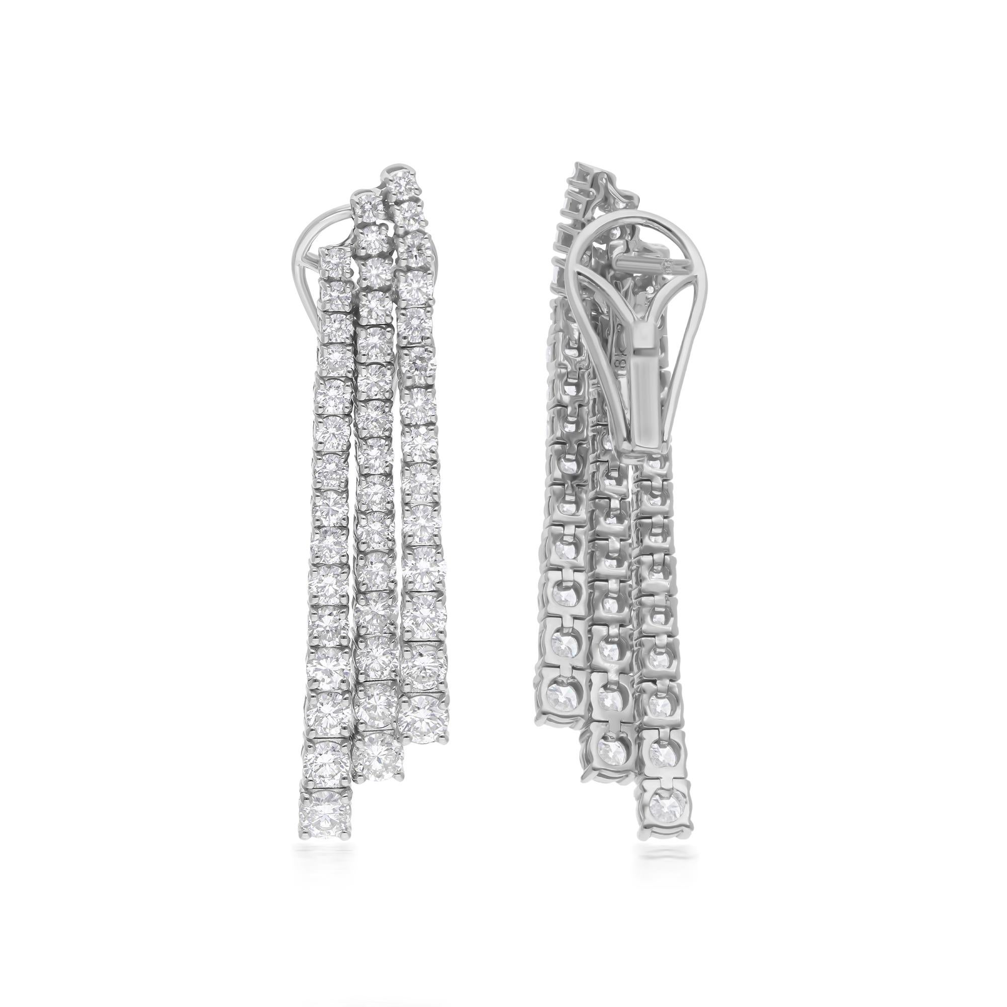 At the heart of each earring, a captivating round diamond takes center stage, radiating brilliance and fire with its impeccable cut and clarity. Surrounding it, two additional lines of smaller diamonds cascade in a mesmerizing pattern, enhancing the