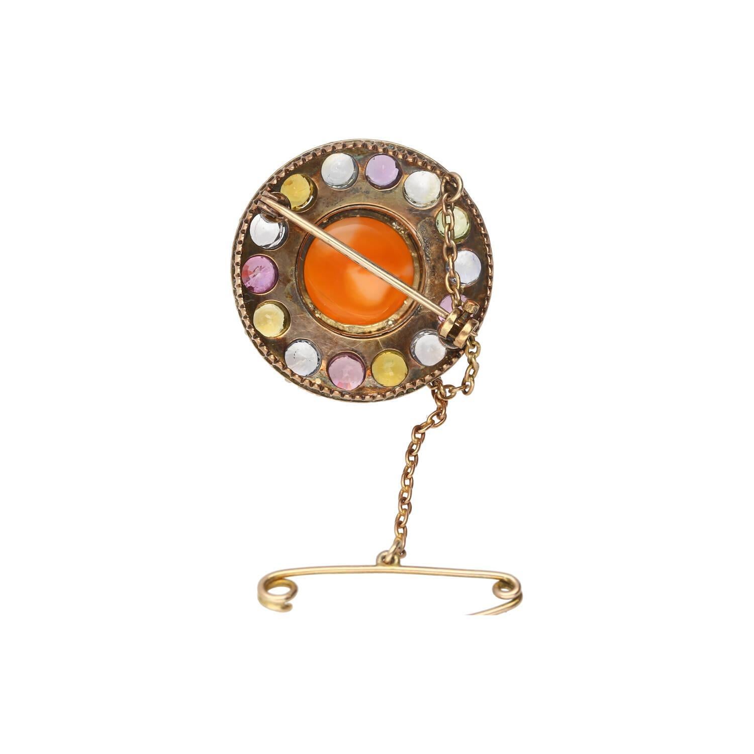 Épingle en opale naturelle avec saphir multicolore en or et argent.

Ce pin's présente une opale orange naturelle de 4,64 carats, taillée en cabochon ovale, et est fixé par un sertissage en épingle. Il est associé à une multitude de saphirs de