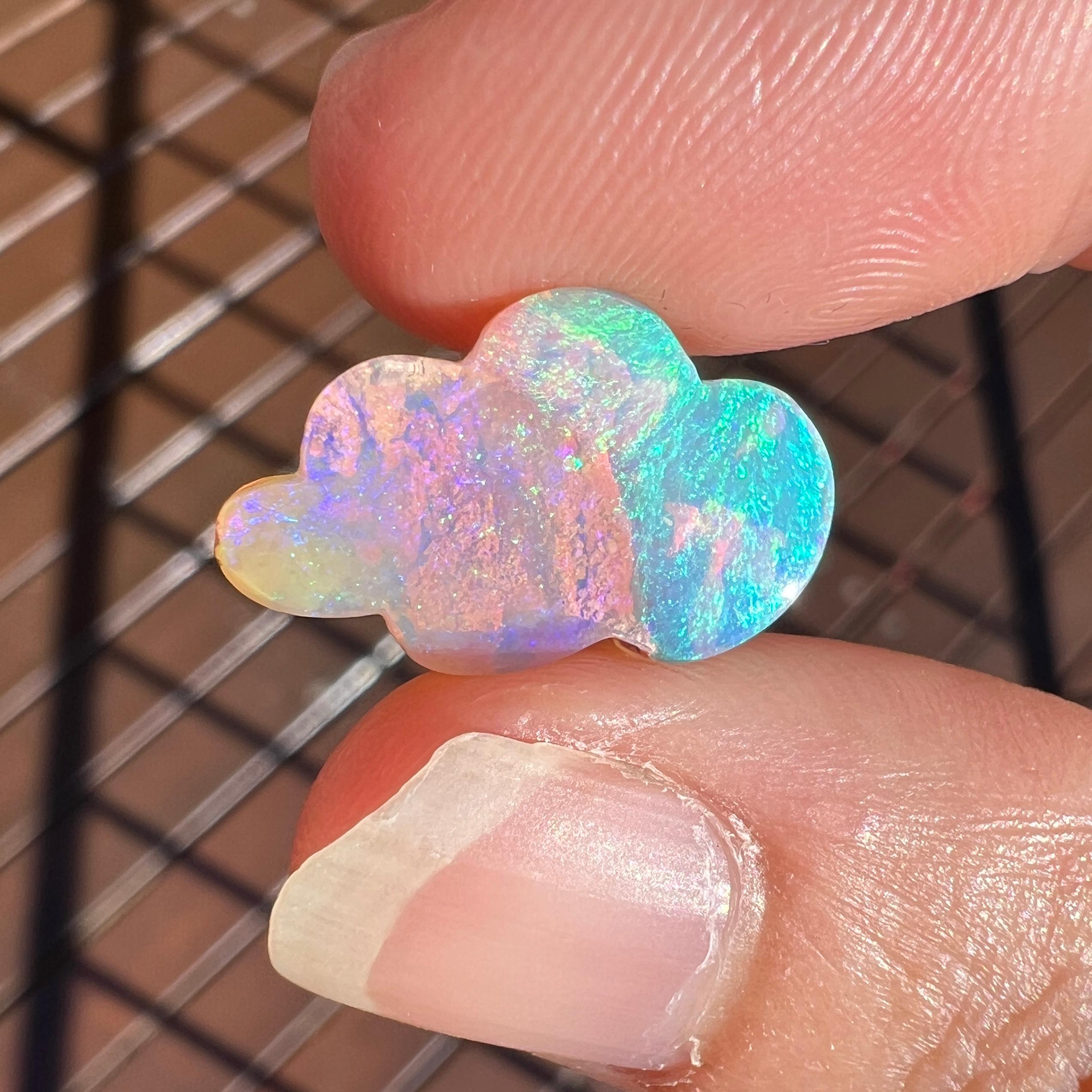This pretty two-tone 4.95 Ct wood replacement opal, carved into a cloud, is a truly exceptional addition to any collection, mined by Sue Cooper herself. Its rarity, coupled with its modern form, captivates connoisseurs with its vibrant play of