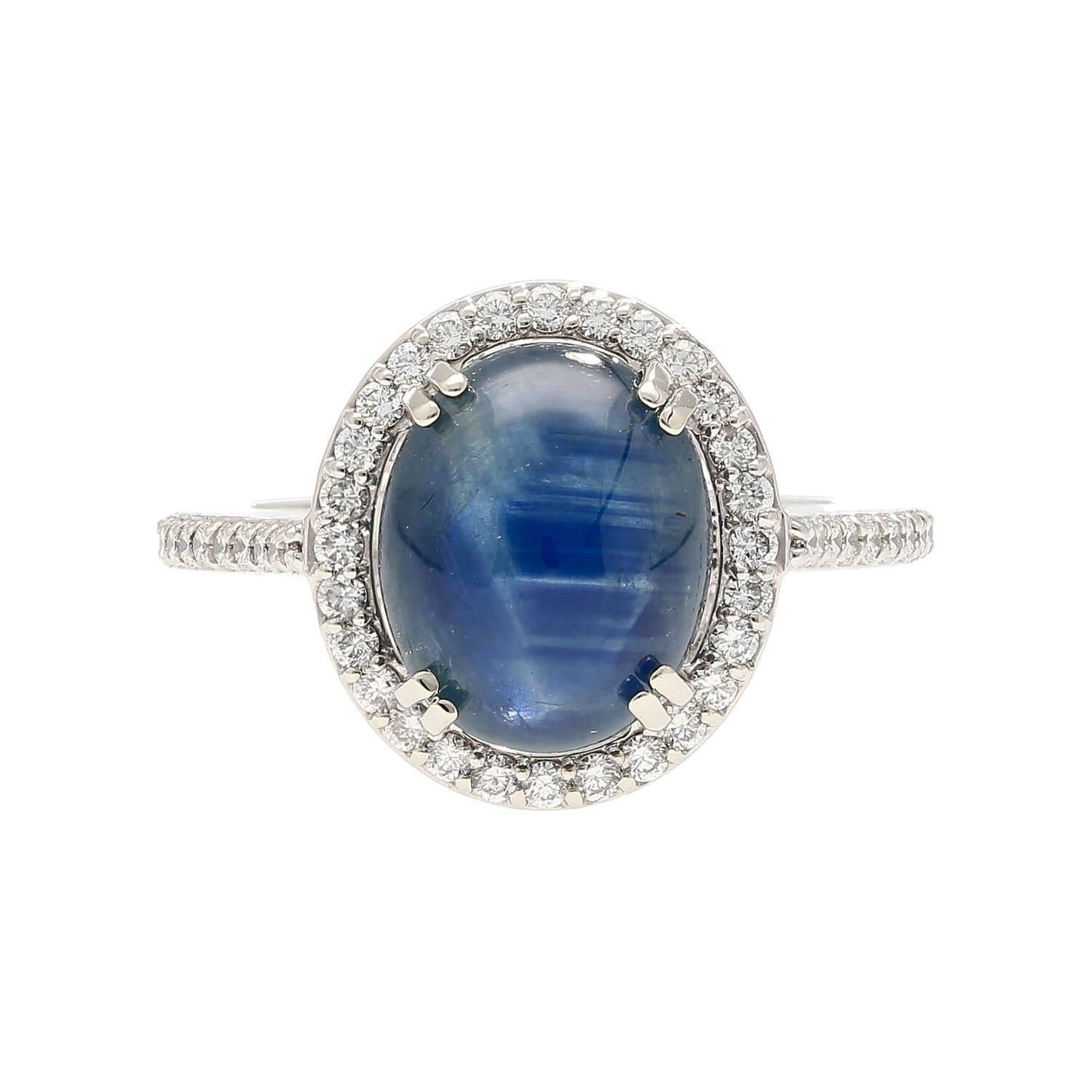 
14K White Gold Ring, weighing 5 grams, meticulously crafted with a prong setting for a timeless appeal.
At the heart of this ring is a mesmerizing 5-carat Round-cut Star Sapphire, radiating a captivating blue hue. Enhancing the allure are two