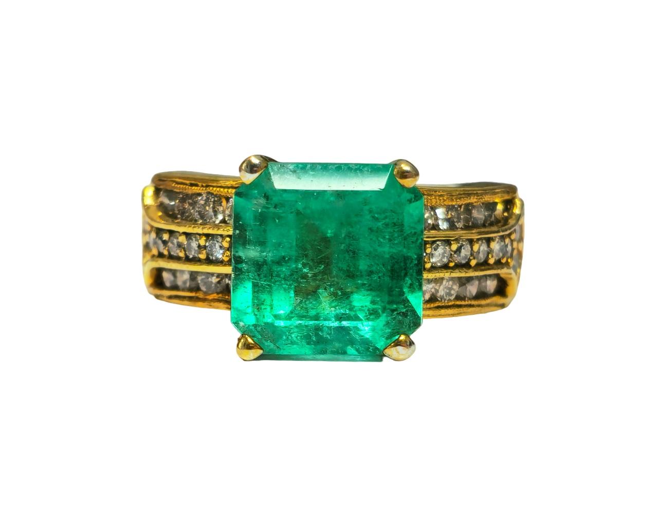 Umarmen Sie die Eleganz mit unserem atemberaubenden Smaragd- und Diamantring aus strahlendem Gelbgold. Der atemberaubende kolumbianische Smaragd mit seinem herrlichen Farbton und seiner intensiven grünen Farbe verleiht diesem Ring eine natürliche