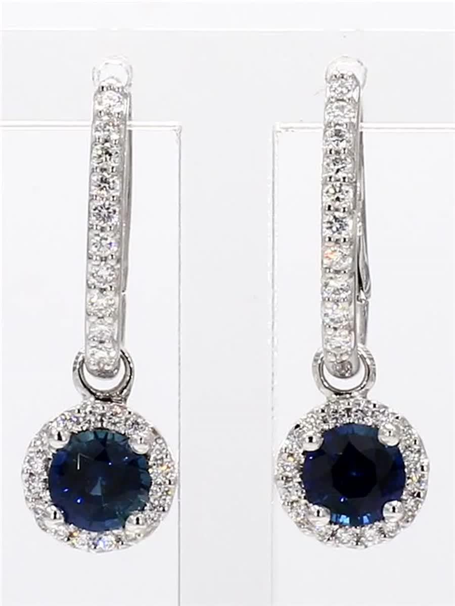 RareGemWorld's classic natural round cut sapphire earrings. Mounted in a beautiful 14K White Gold setting with natural round cut blue sapphires. The sapphires are surrounded by a single halo of natural round white diamond melee as well as diamonds