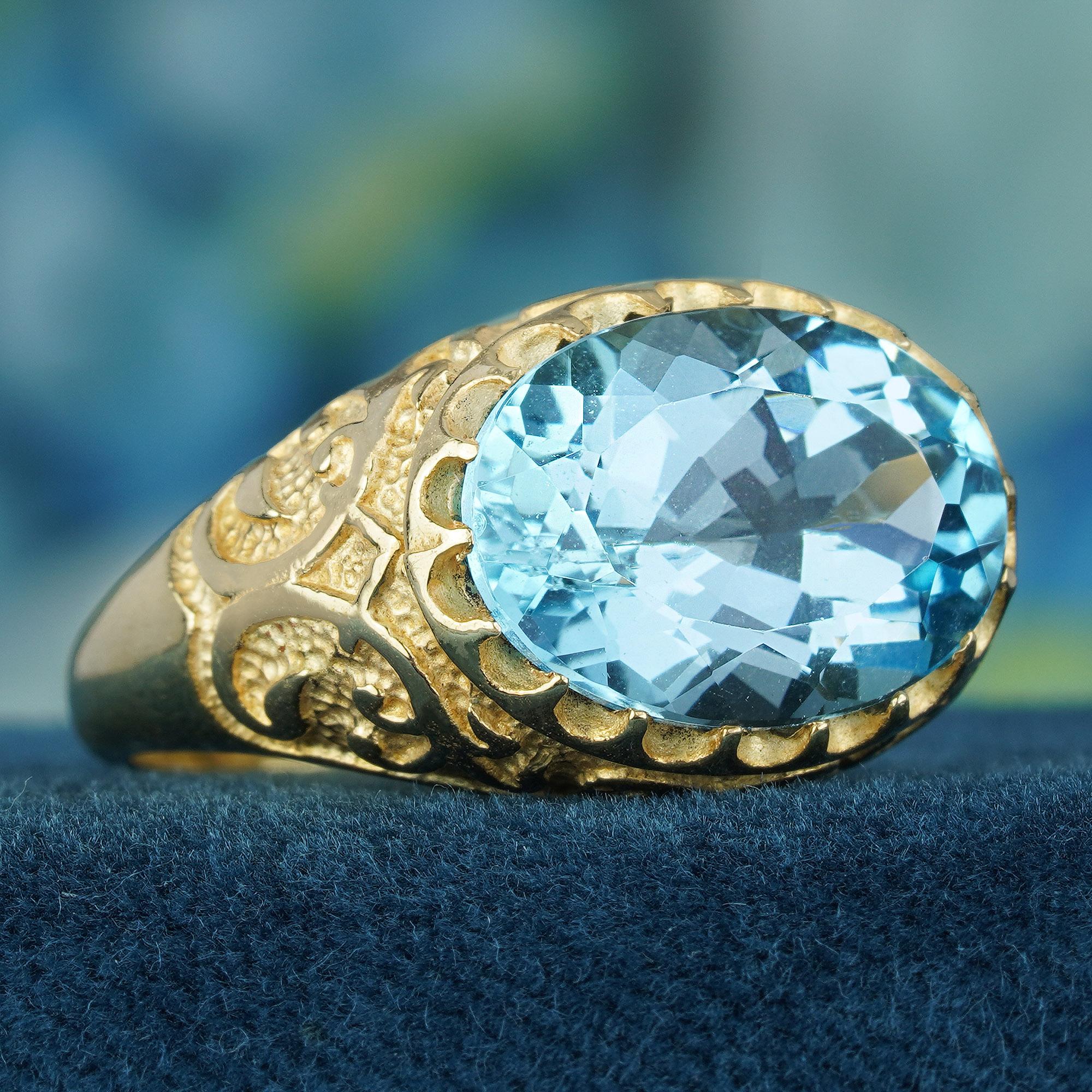 Der ovale himmelblaue Topas von 7,25 Karat ist in ein massives Gelbgoldband eingebettet, das mit komplizierten Details und in das Metall eingravierten Vintage-Designs versehen ist, die dem Ring Vintage-Charme verleihen. Die Muster sind eine Hommage