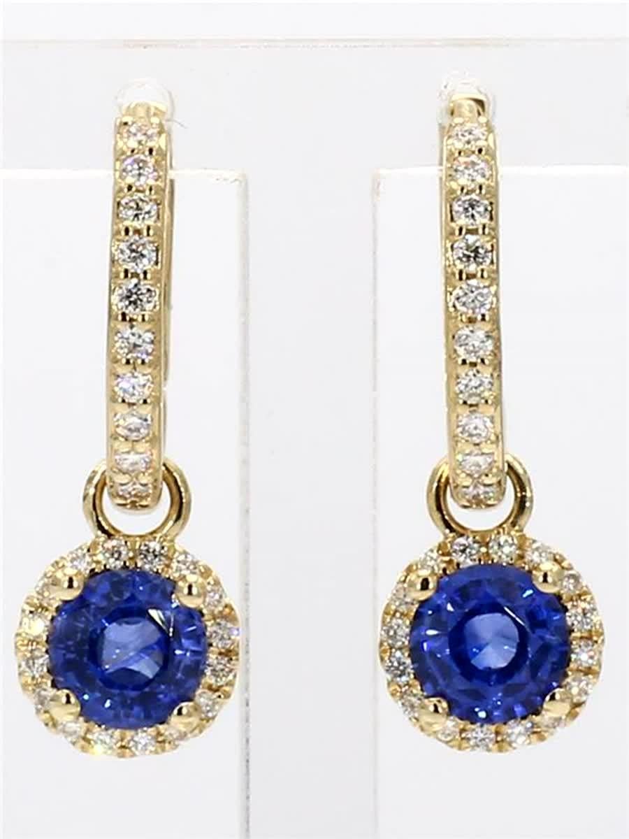 RareGemWorld's classic natural round cut sapphire earrings. Mounted in a beautiful 14K Yellow Gold setting with natural round cut blue sapphires. The sapphires are surrounded by a single halo of natural round white diamond melee as well as diamonds