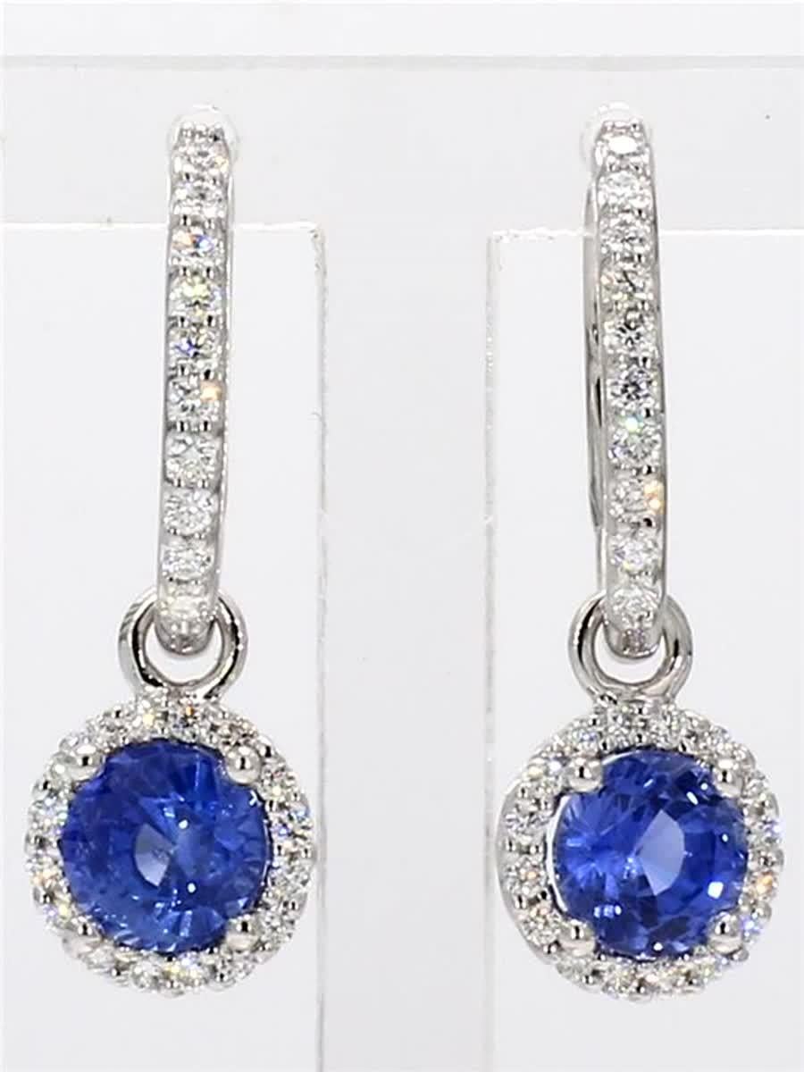RareGemWorld's classic natural round cut sapphire earrings. Mounted in a beautiful 14K White Gold setting with natural round cut blue sapphires. The sapphires are surrounded by a single halo of natural round white diamond melee as well as diamonds
