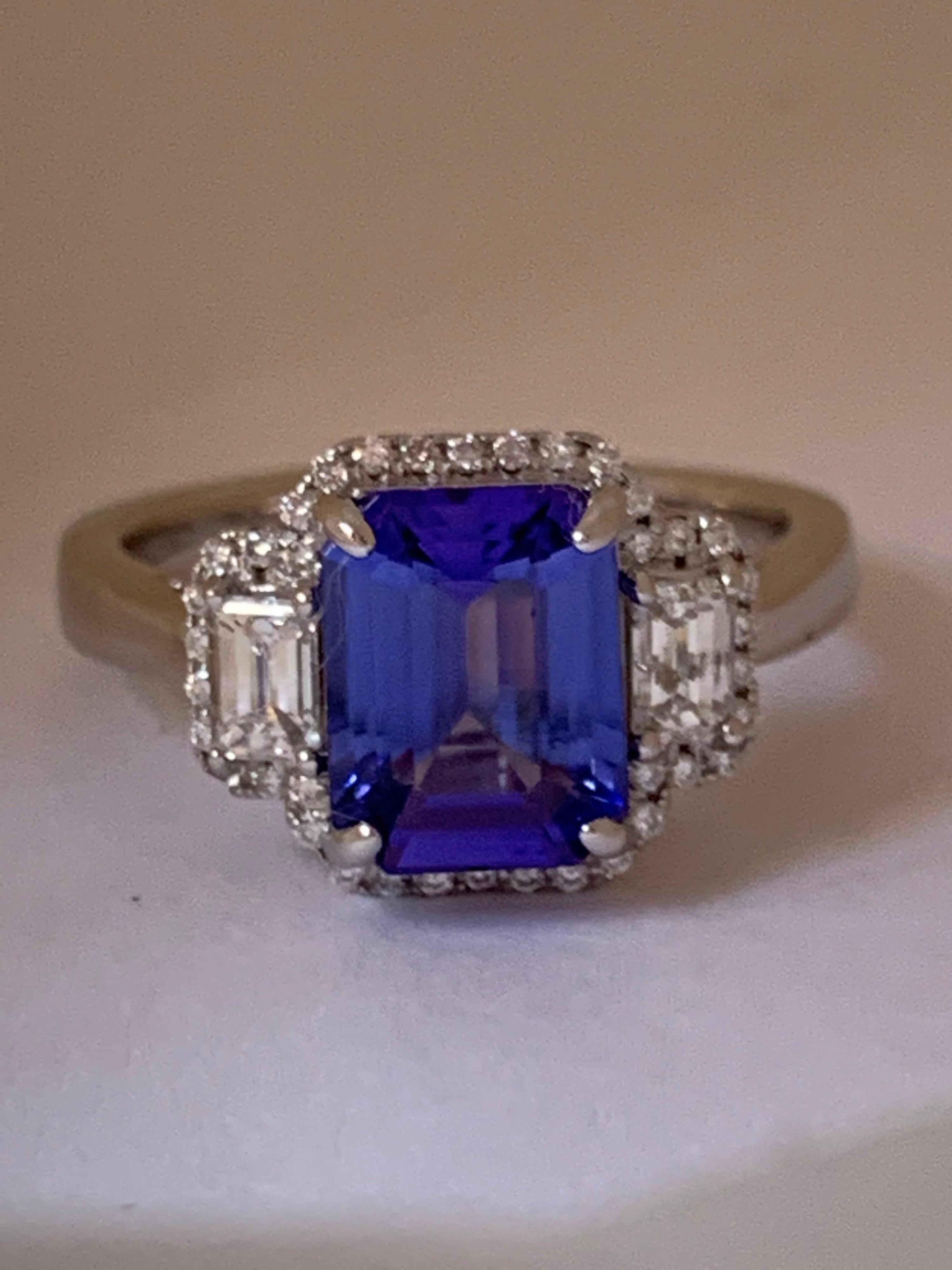 Natural AAA Quality 2.75 carat Tanzanite Emerald cut shape and 0.50 carat round and two emerald cut diamonds on the side is set in 14 Karat white gold , handcrafted one of a kind Ring, The Ring is size 7 but can be resized if needed.