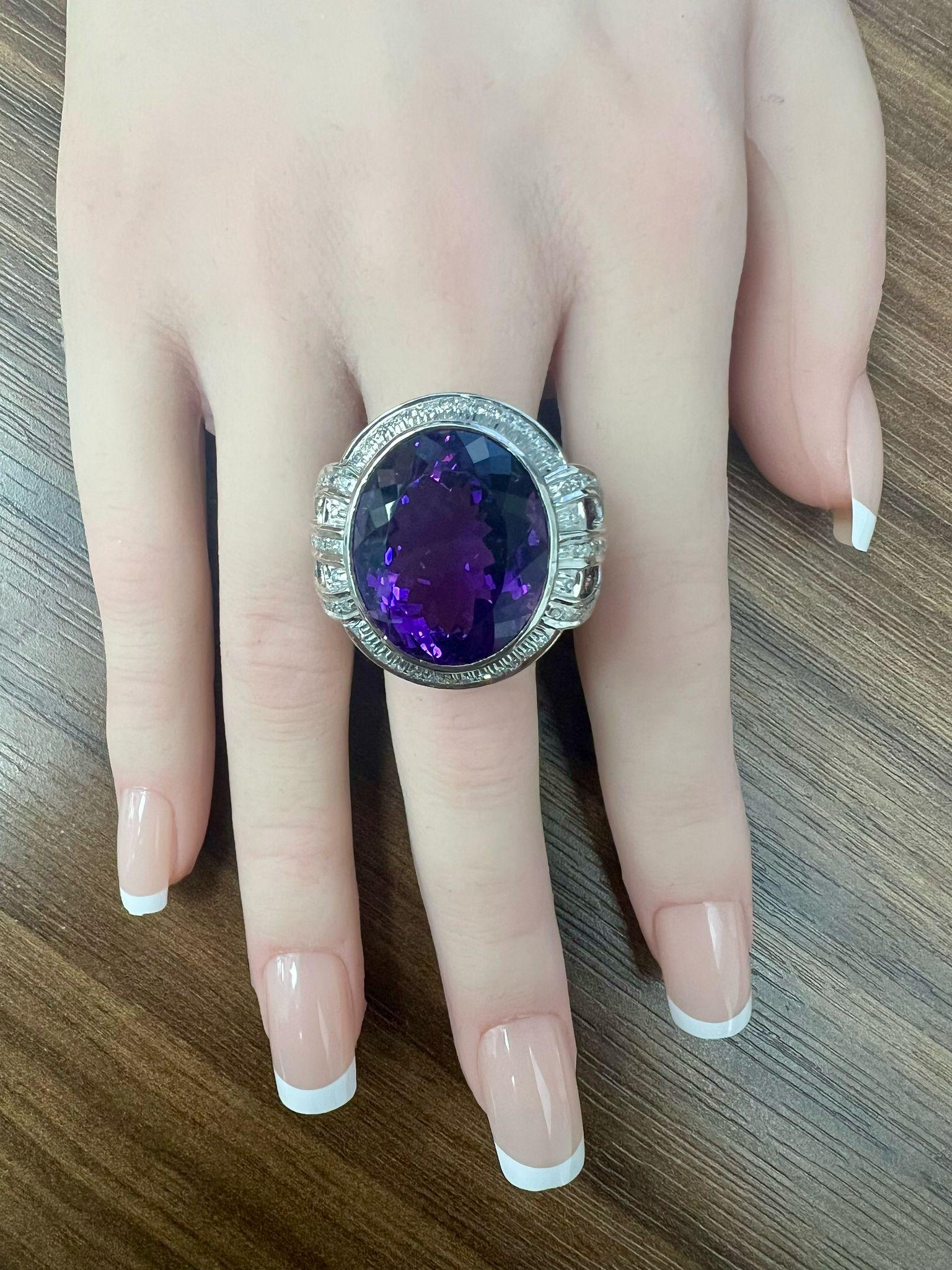 Descubre el encanto de este impresionante anillo de amatista, con una gran gema de amatista de 28,30 quilates de talla ovalada que irradia un intenso tono púrpura. Rodeada de intrincados detalles de diamantes de 0,54 quilates, esta pieza es perfecta