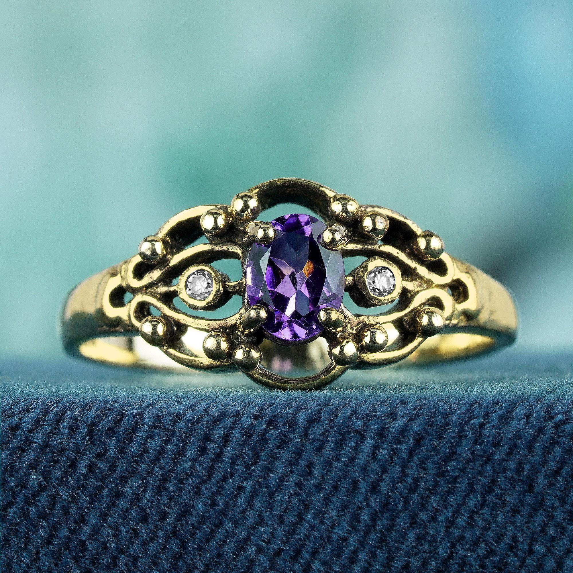 The ring is crafted from yellow gold and features a vintage style design. The centerpiece is a prong-set, oval-shaped faceted amethyst with a purple hue. Maximizing its sparkle with two small round diamonds flank each side, maximizing its sparkle