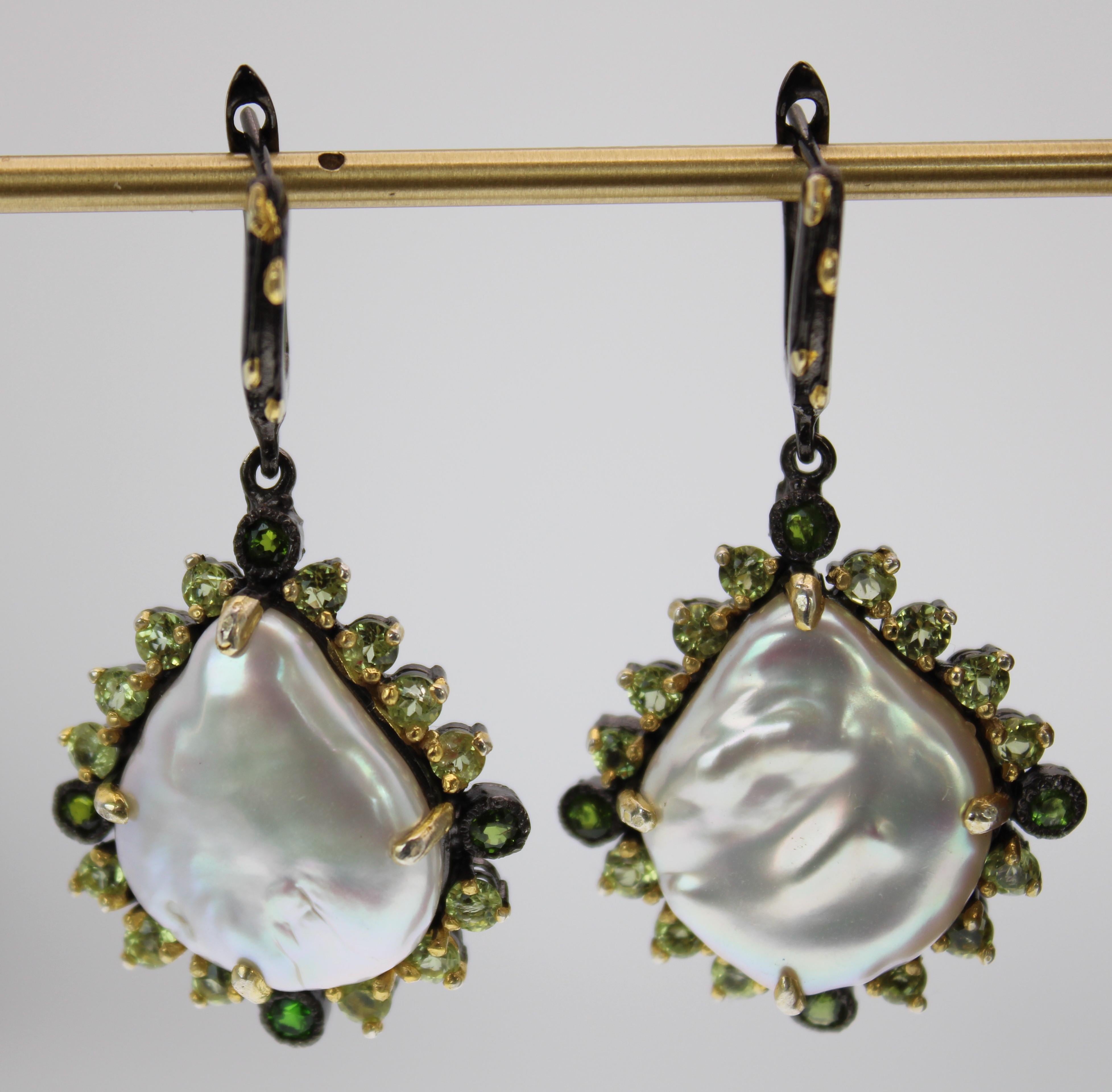 Natural Baroque Pearl Earrings with beautiful iridescent color. The pearls are surrounded by 18 green onyx and peridot round stones. The earrings are set in mixed metal showcasing black rhodium and gold plating details over sterling silver. 
They