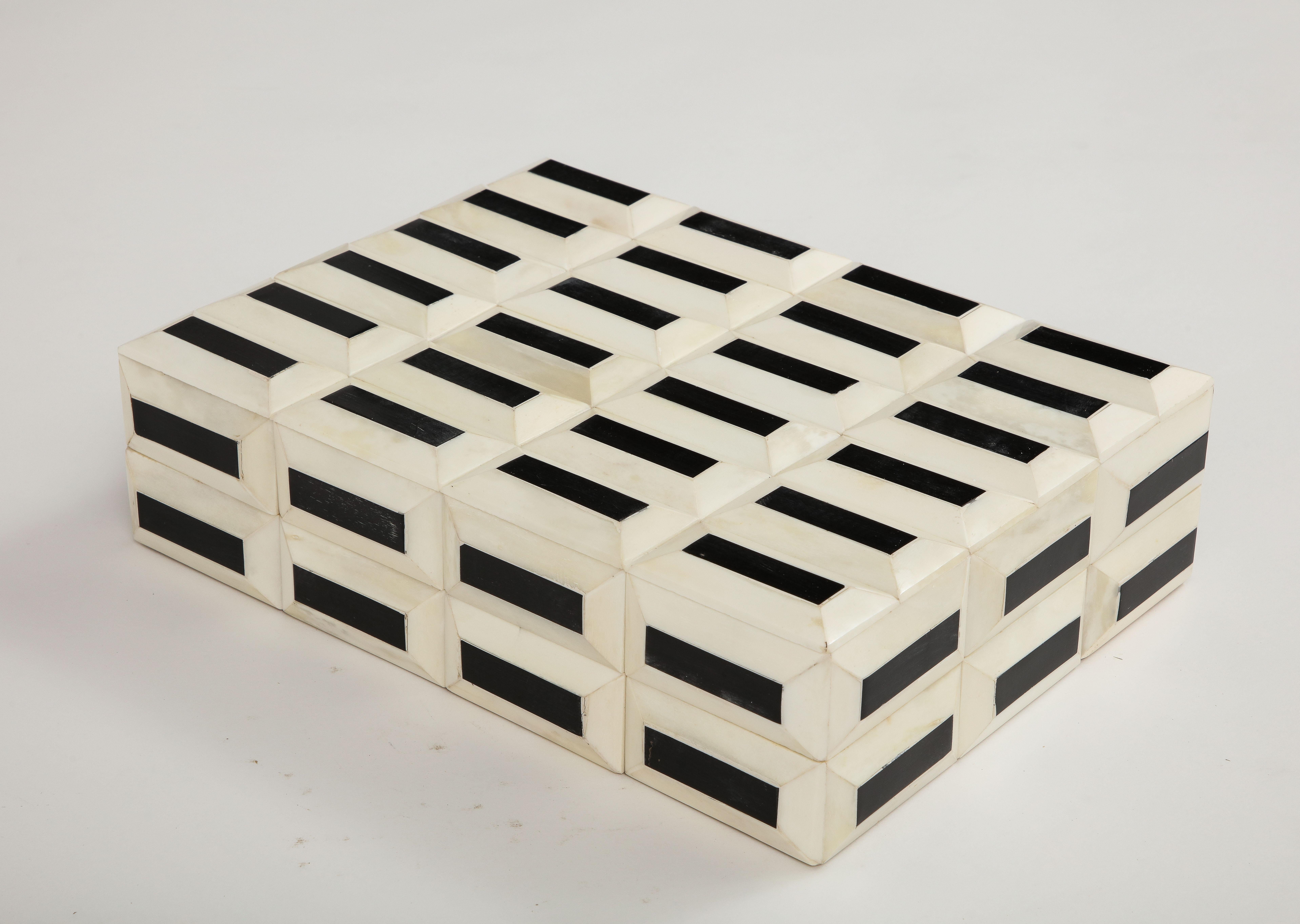 Hand made dimensional bone box with hand set black centers. Rectangular pieces form a dimensional facade, lined in wood. A great addition to any coffee table to store remote controls or desk.