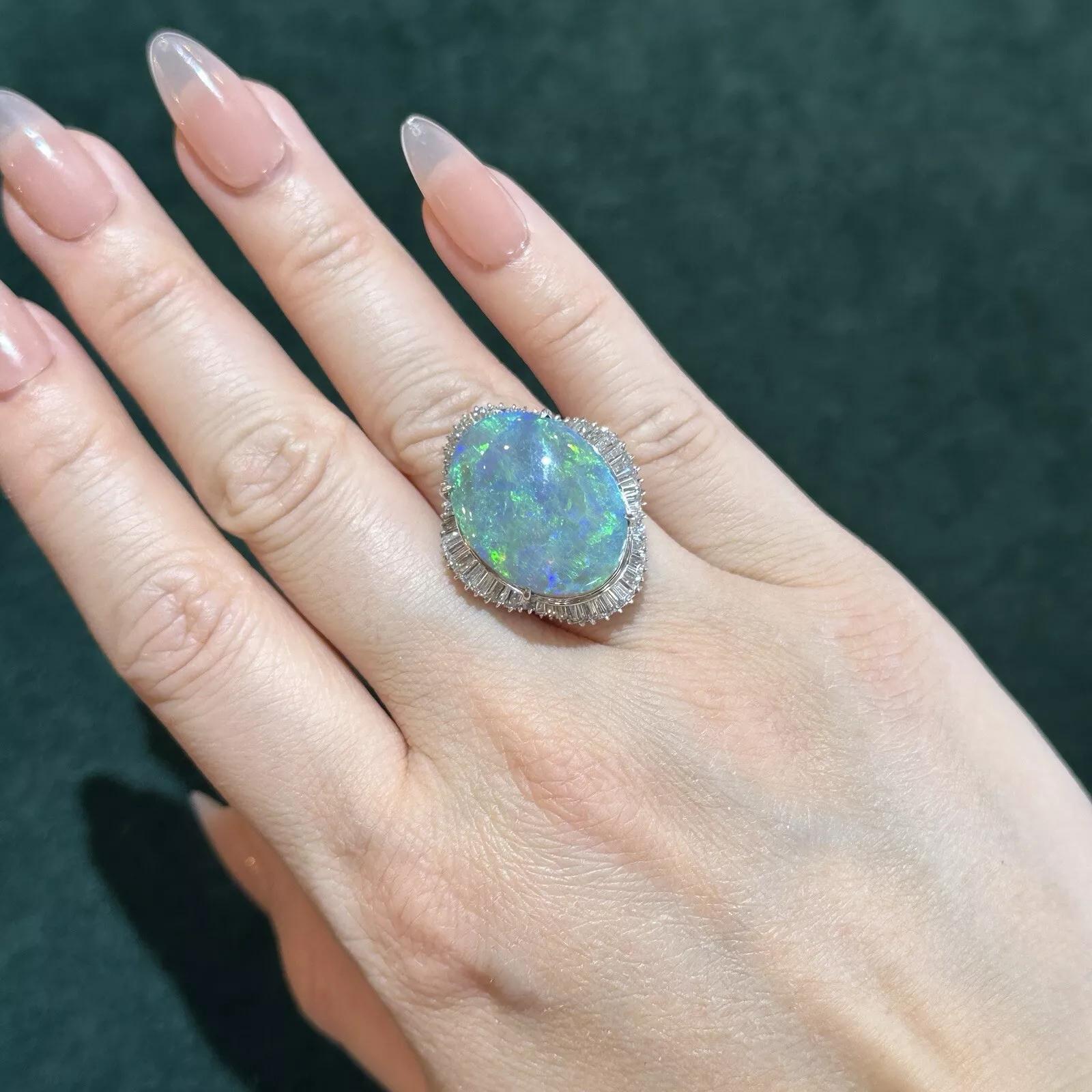 Natural Black Opal 15.60 carat and Diamond Cocktail Ring in Platinum

Large Black Opal and Diamond Ring features Natural Oval Cabochon Black Opal weighing 15.60 carats with flashes of blues, greens, and orange surrounded by Baguette Diamonds set in