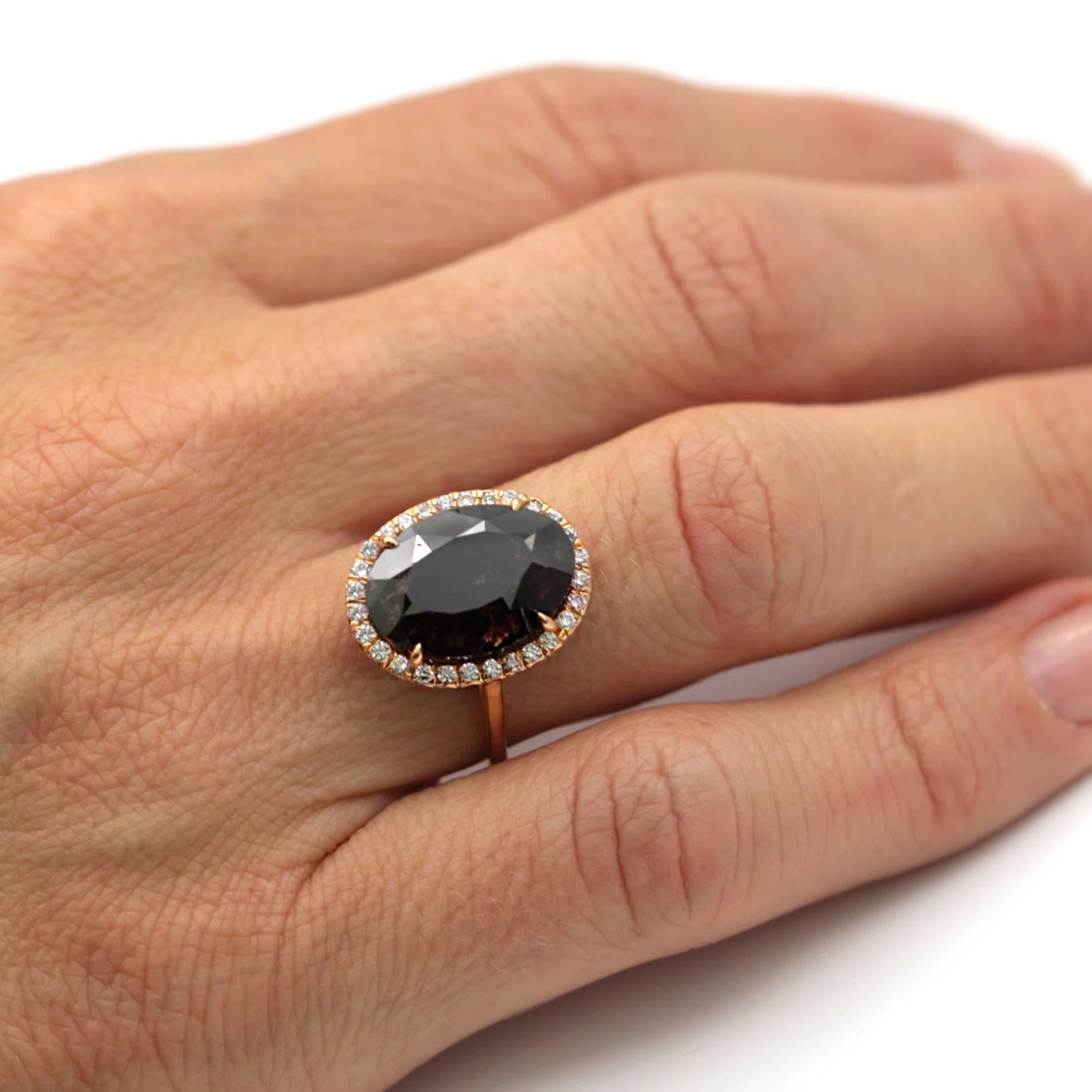 Natural black oval shaped diamond weighing 8.50 carats. The diamond is set in a 20 karat rose gold mounting with twenty-eight round light pink diamonds surrounding the center diamond. The ring is a size 6.5.