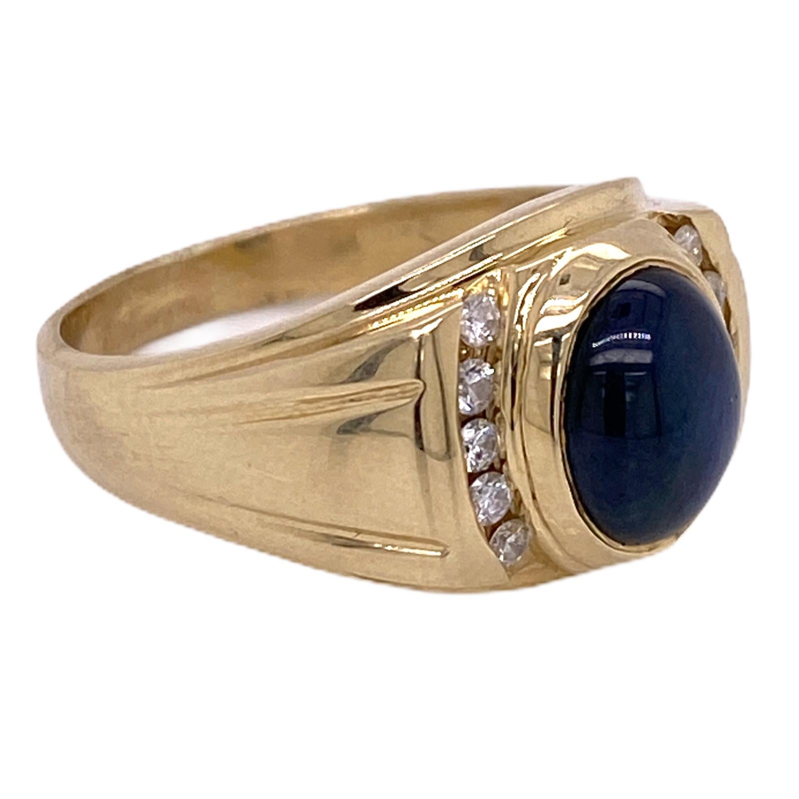 Men's cabochon blue sapphire diamond ring fashioned in 14 karat yellow gold. The natural blue cabochon sapphire weighs approximately 4.50 carats and is flanked by 10 round brilliant cut diamonds weighing .30 carat total weight. The ring measures