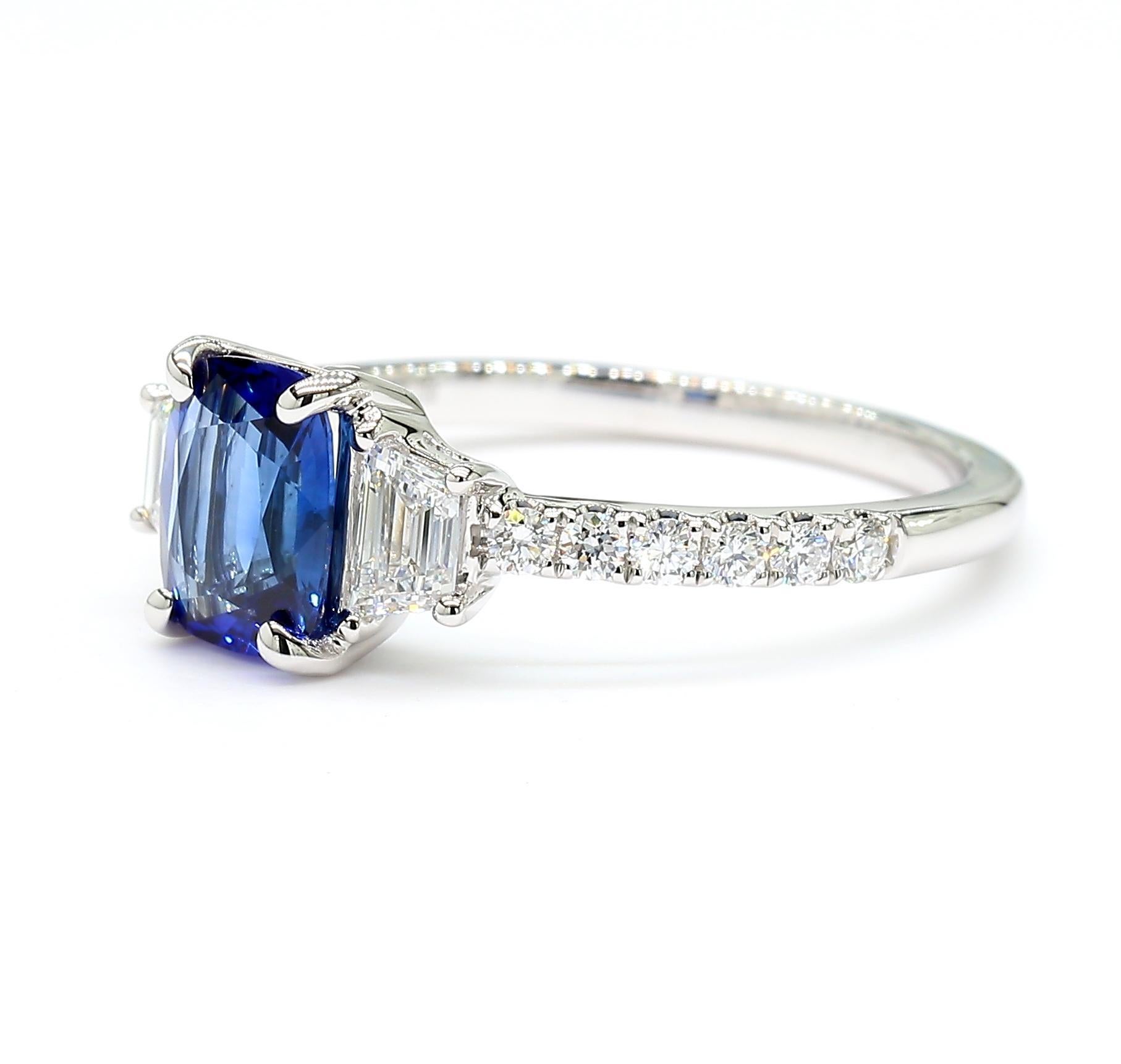 La magnifique bague en saphir de Raregemworld. Monté dans une belle monture en or blanc 18 carats avec un saphir bleu naturel de taille coussin. Le saphir est entouré de diamants blancs naturels de taille trapézoïdale et d'une mêlée de diamants