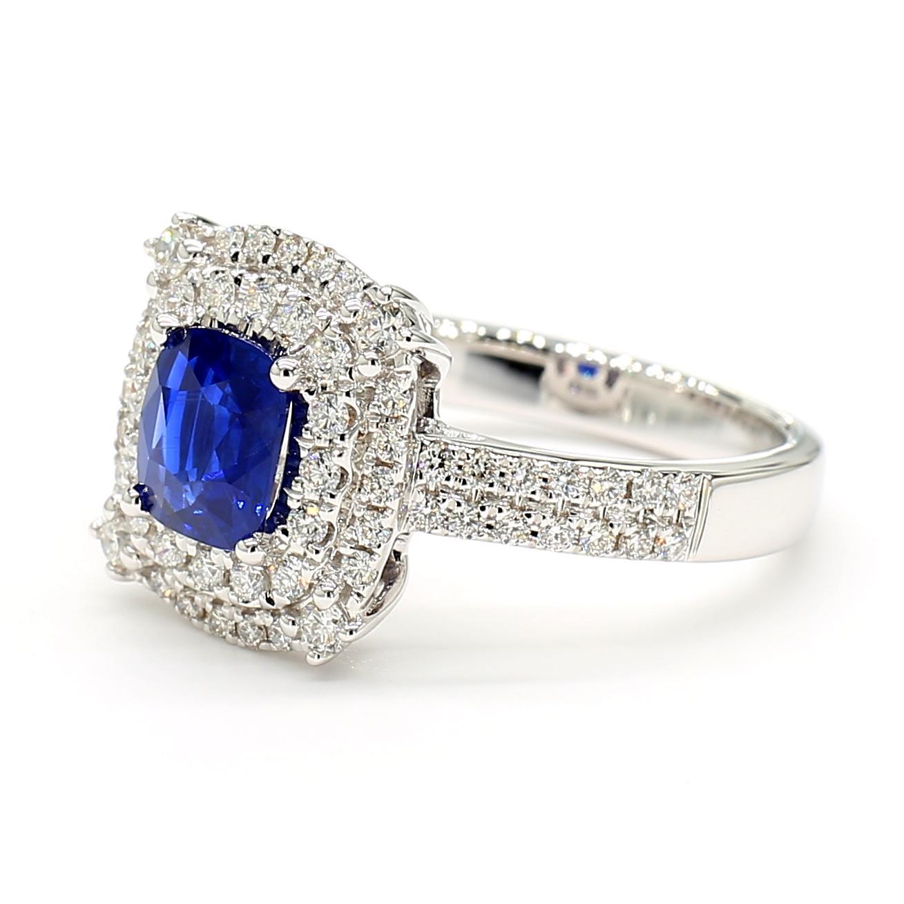 Precioso anillo de zafiro de RareGemWorld. Montada en un precioso engaste de oro blanco de 18 quilates con un zafiro azul natural talla cojín. El zafiro está rodeado de melee de diamantes blancos redondos naturales. Este anillo impresionará y