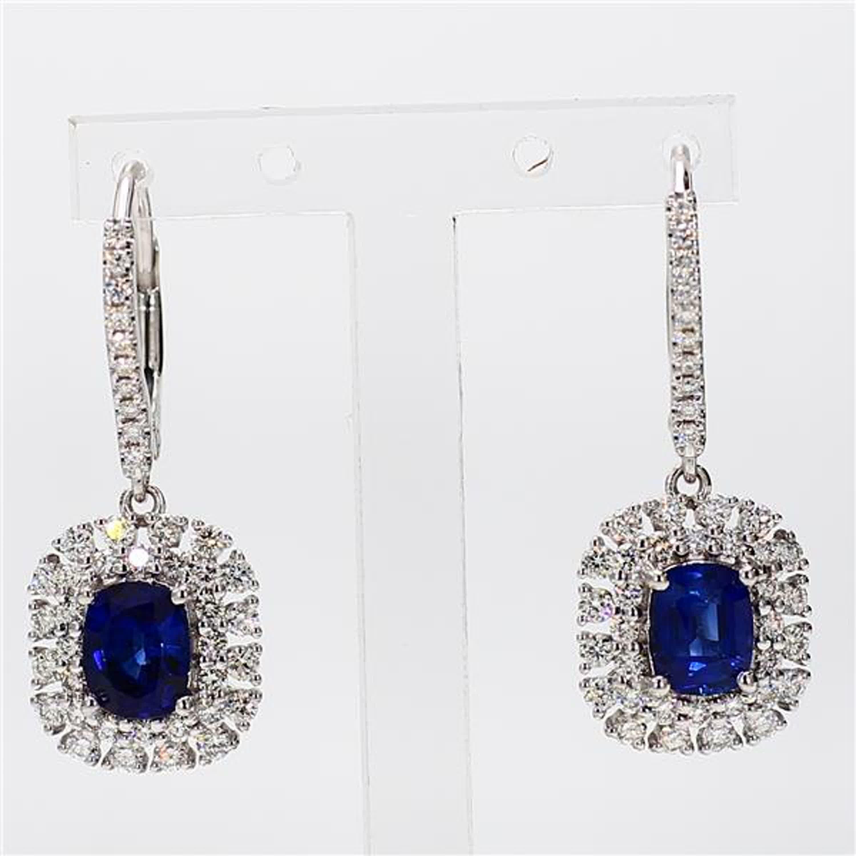 RareGemWorld's classic sapphire earrings. Mounted in a beautiful 18K White Gold setting with natural cushion cut blue sapphires. The sapphires are surrounded by natural round white diamond melee as well as diamonds throughout the earrings. These