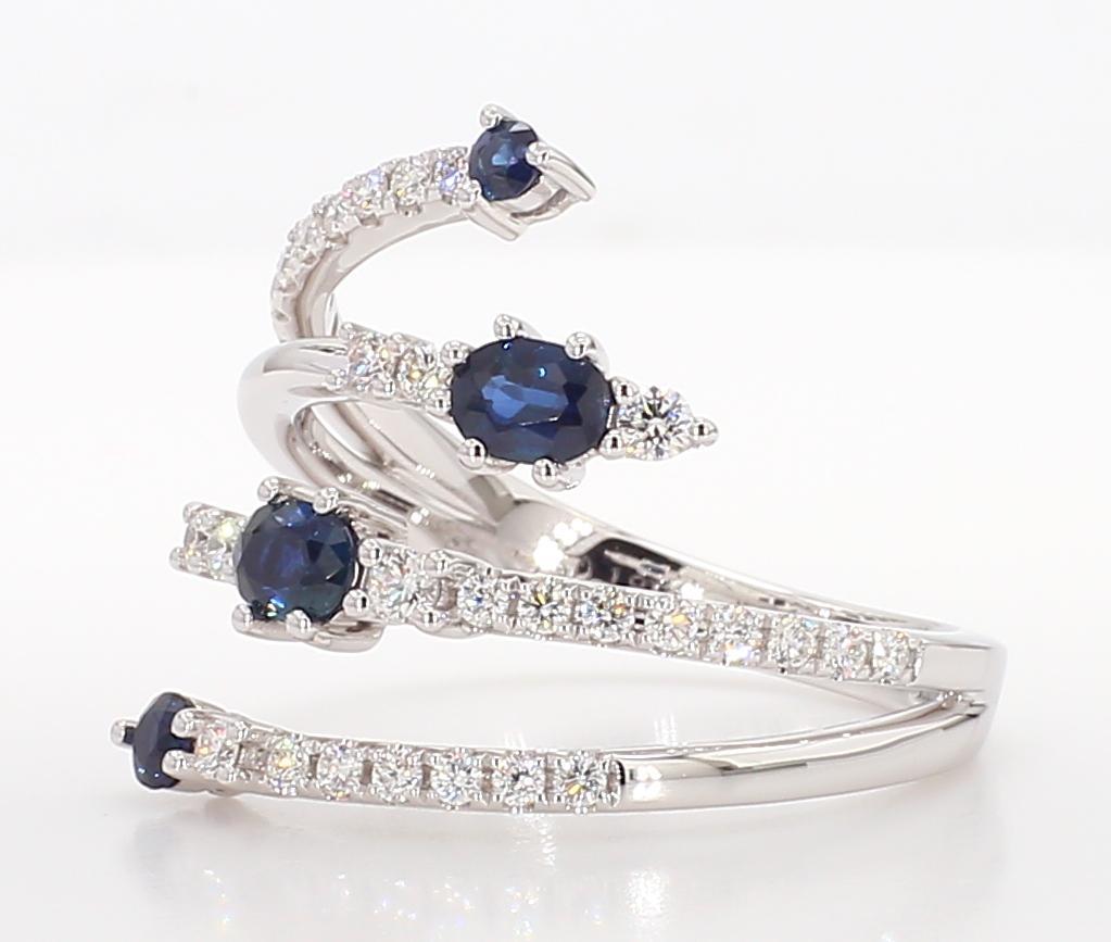 RareGemWorld's intriguing sapphire ring. Mounted in a beautiful 18K White Gold setting with two natural oval cut blue sapphire and two natural round cut blue sapphires. The sapphire is surrounded by round natural white diamond melee. This ring is