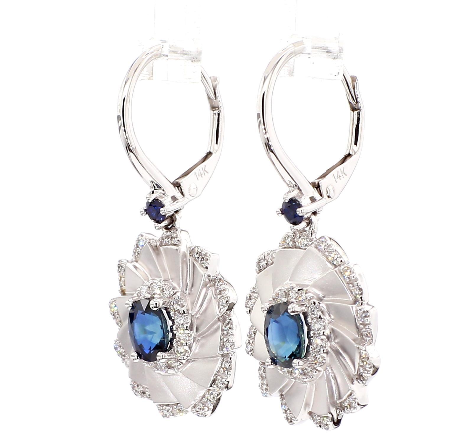 Gli orecchini classici con zaffiro di RareGemWorld. Montato in una splendida montatura in oro bianco 14 carati con zaffiri blu naturali di taglio ovale. Gli zaffiri sono circondati da due zaffiri blu naturali a taglio rotondo e da un diamante bianco