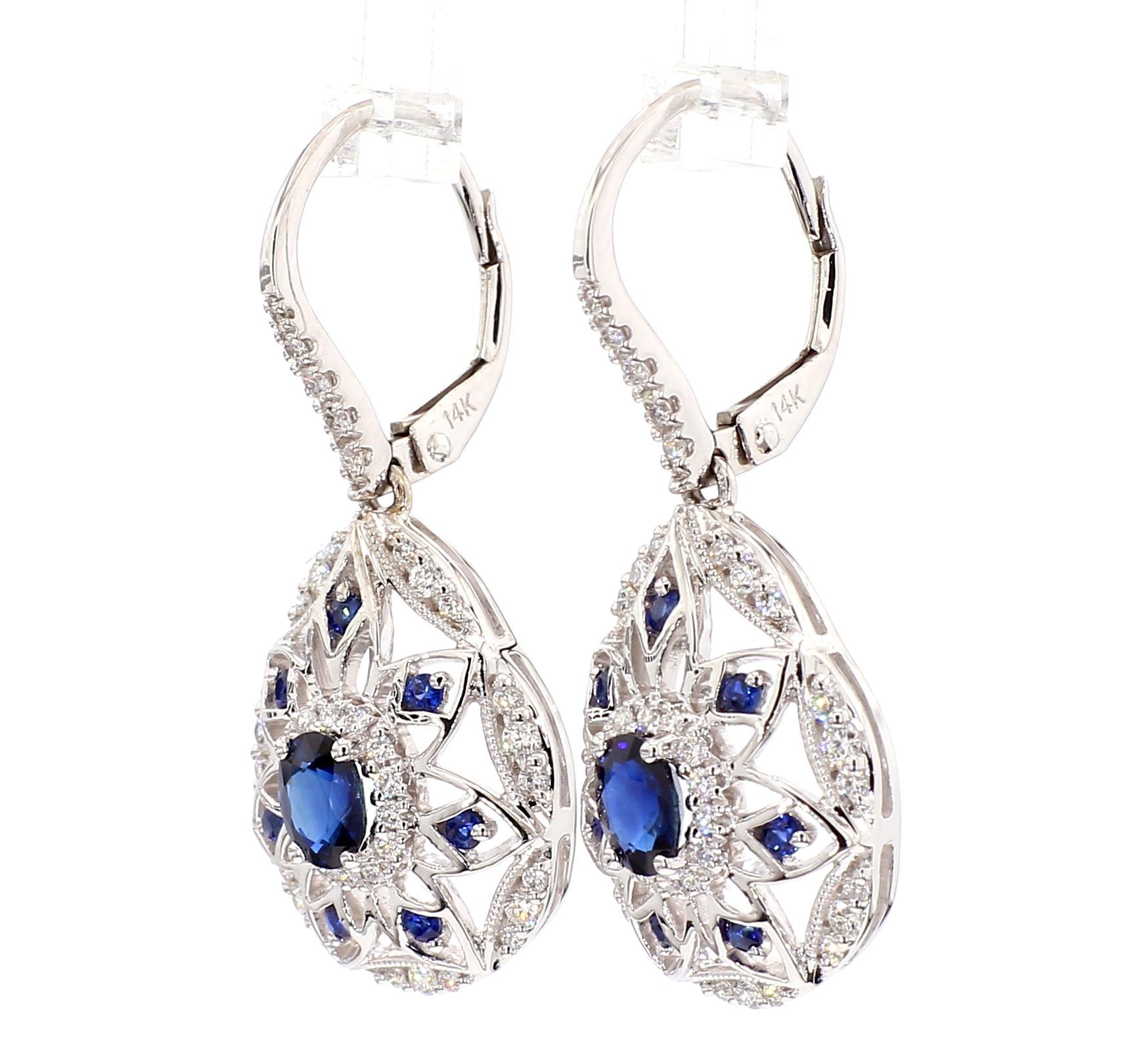 RareGemWorld's classic sapphire earrings. Mounted in a beautiful 14K White Gold setting with natural oval cut blue sapphires. The sapphires are surrounded by natural round cut blue sapphires and natural round cut white diamond melee. These earrings