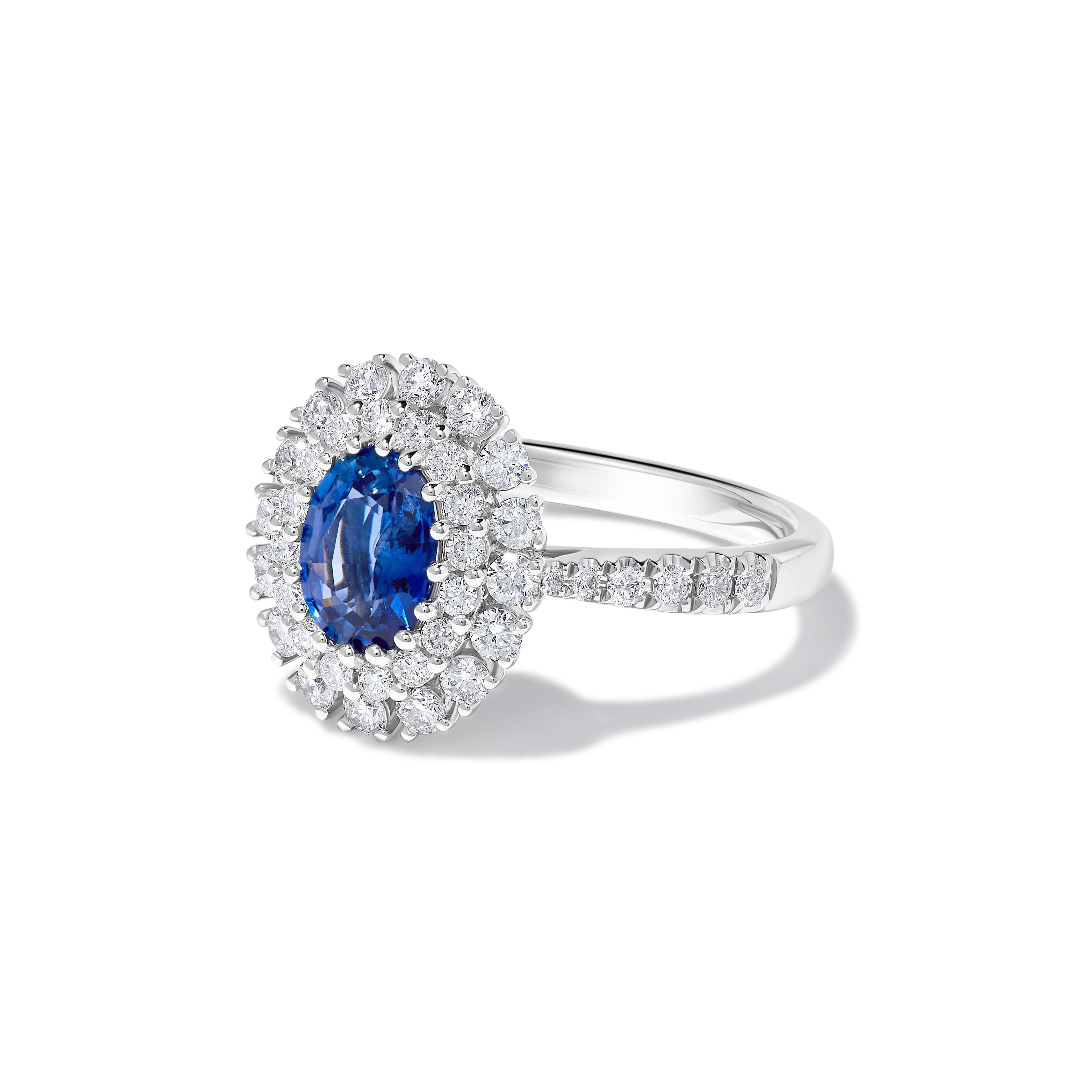 RareGemWorld's beautiful sapphire ring. Mounted in a beautiful 18K White Gold setting with a natural oval cut blue sapphire. The sapphire is surrounded by natural round white diamond melee. This ring is guaranteed to impress and enhance your
