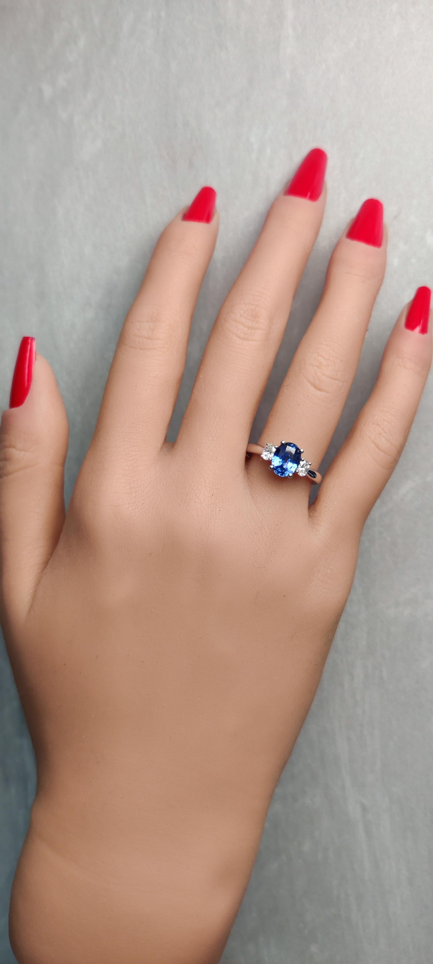 RareGemWorld's classic sapphire ring. Mounted in a beautiful 14K White Gold setting with a natural oval cut blue sapphire. The sapphire is surrounded by two natural oval cut white diamonds. This ring is guaranteed to impress and enhance your