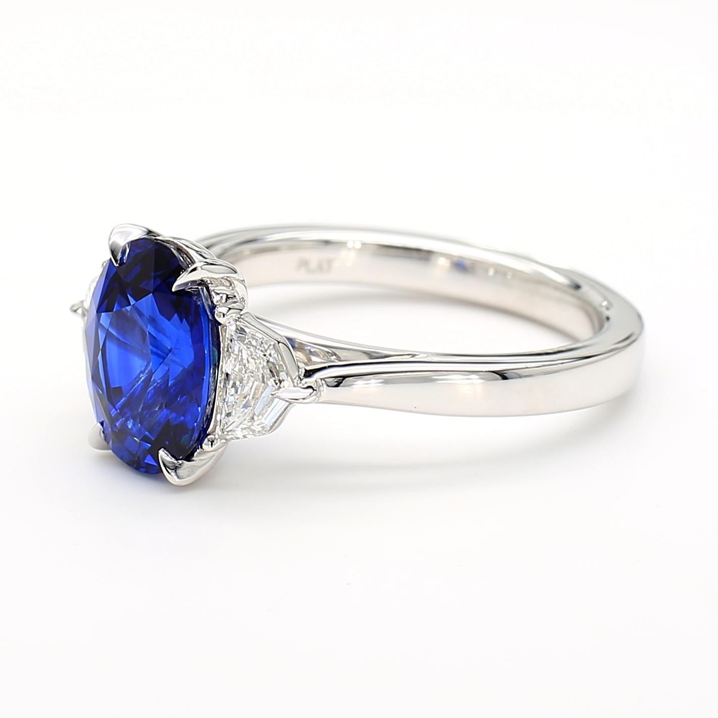 Der schöne Saphirring von RareGemWorld. Montiert in einer schönen Platinfassung mit einem natürlichen blauen Saphir im Ovalschliff. Der Saphir ist von zwei weißen Diamanten im natürlichen Epaulettenschliff umgeben. Dieser Ring wird Sie garantiert